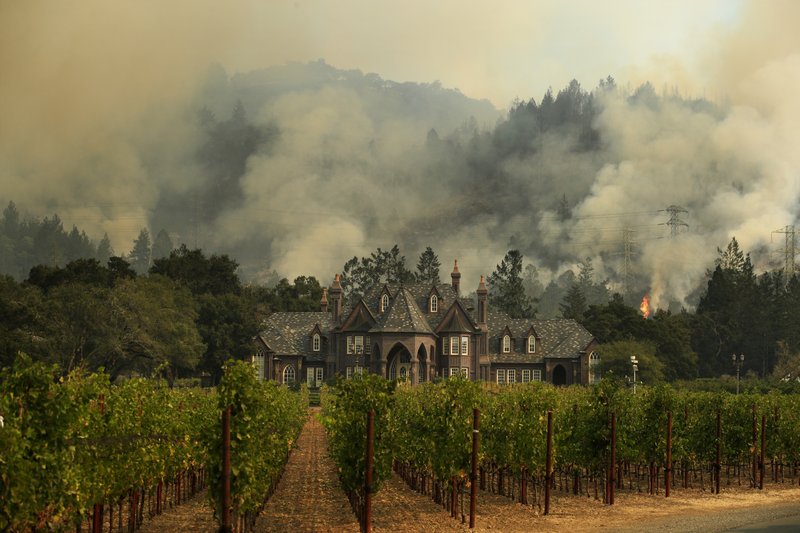 A wildfire burns behind a winery Saturday, Oct. 14, 2017, in Santa Rosa, Calif. Fire crews made progress this week in their efforts to contain the massive wildfires in California wine country, but officials say strong winds are putting their work to the test. (AP Photo/Jae C. Hong)