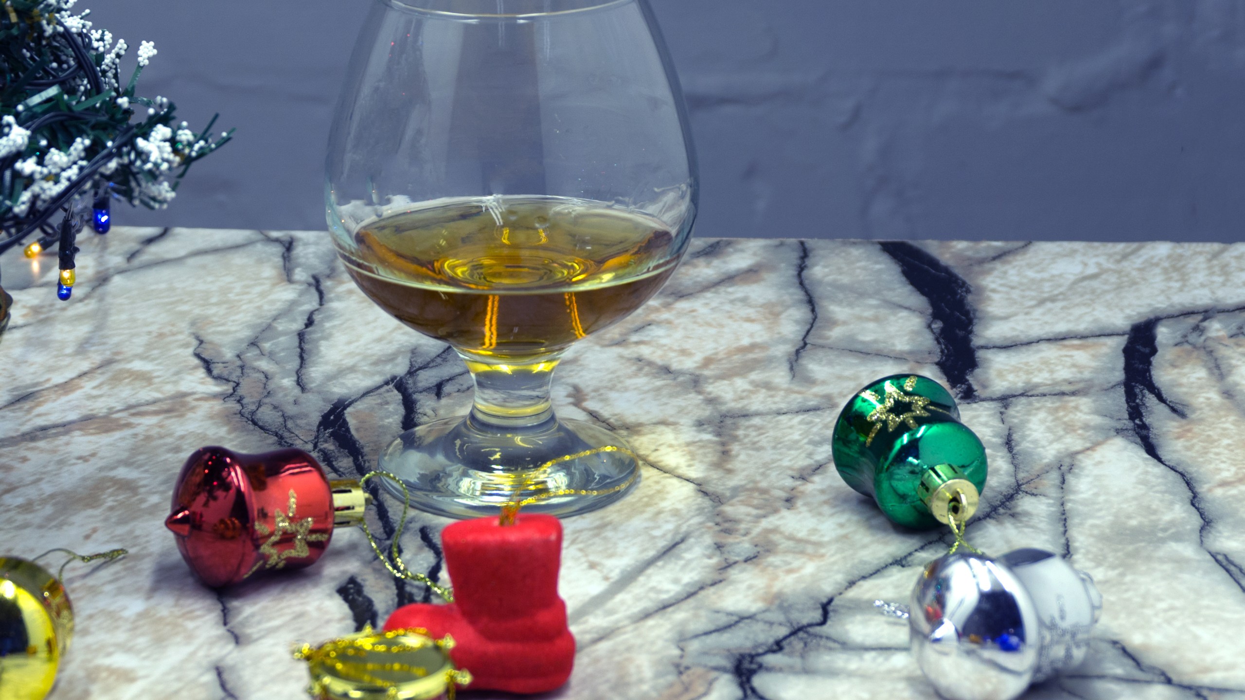 Glass of whiskey with ice, a car key and a toy car over a reindeer with lights at the