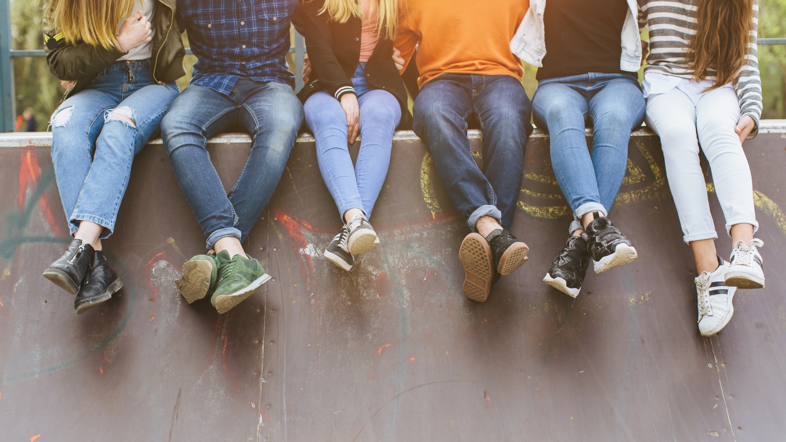 Summer holidays and teenage concept - group of smiling teenagers with skateboard hanging out outside.