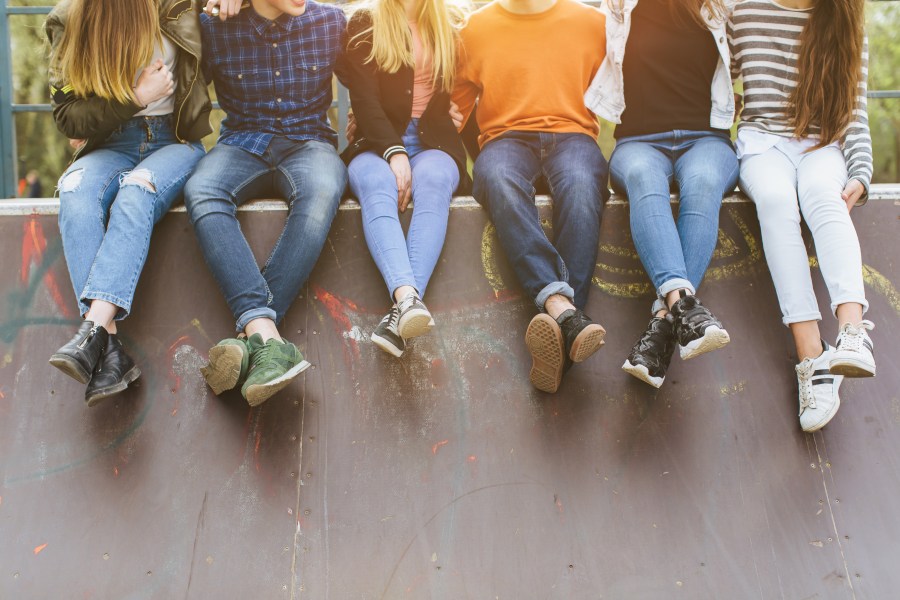 Summer holidays and teenage concept - group of smiling teenagers with skateboard hanging out outside.