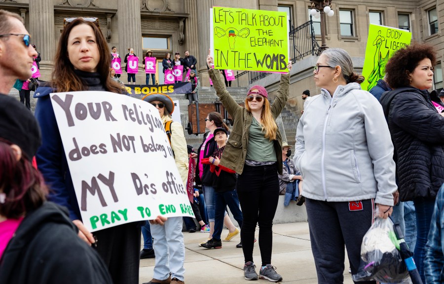 FILE - Boise, Idaho, resident Autumn Myers holds a sign with the Republican Party elephant symbol inside the outline of a uterus that reads, "Let's talk about the elephant in the womb," during a Planned Parenthood rally for abortion rights at the Idaho Statehouse in downtown Boise, May 14, 2022. Idaho lawmakers are considering a measure that would bar adults from taking minors to obtain an abortion without their parent's consent. (Sarah A. Miller/Idaho Statesman via AP, File)