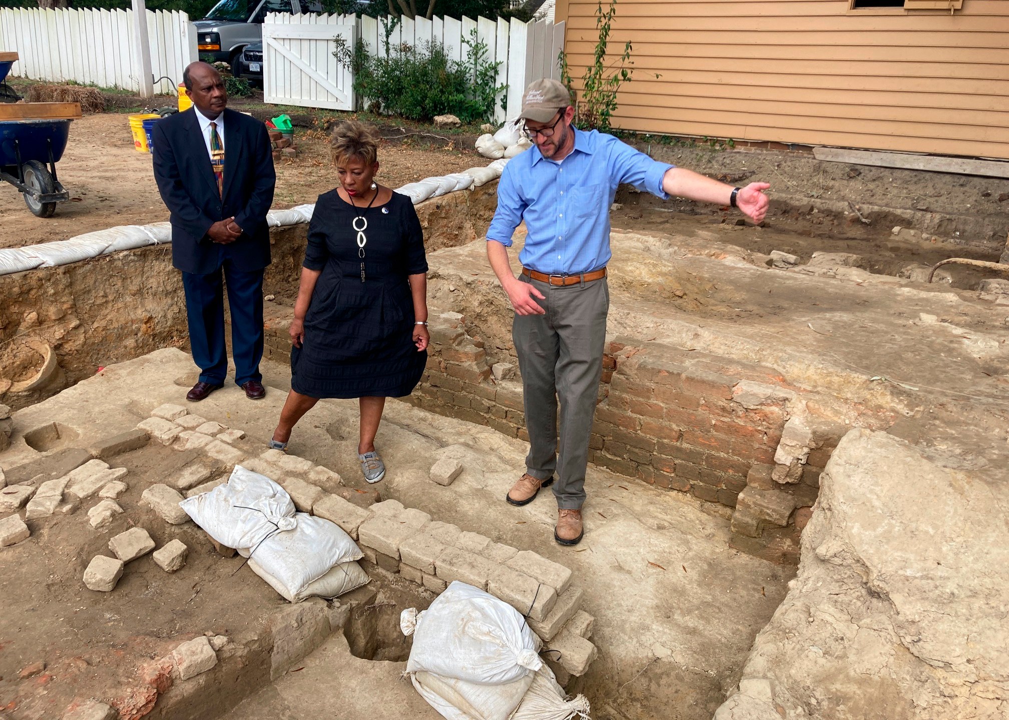 FILE - From left, Reginald F. Davis, pastor of First Baptist Church, Connie Matthews Harshaw, a member of First Baptist, and Jack Gary, Colonial Williamsburg's director of archaeology, stand at the brick-and-mortar foundation of one the oldest Black churches in the U.S. on Oct. 6, 2021, in Williamsburg, Va. Experts announced Thursday, April 6, 2023, that three men whose graves were found at the site were members of the church in the early 19th Century. (AP Photo/Ben Finley, File)