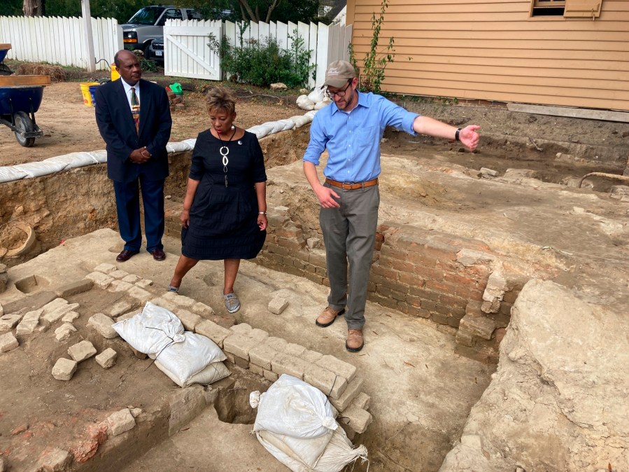 FILE - From left, Reginald F. Davis, pastor of First Baptist Church, Connie Matthews Harshaw, a member of First Baptist, and Jack Gary, Colonial Williamsburg's director of archaeology, stand at the brick-and-mortar foundation of one the oldest Black churches in the U.S. on Oct. 6, 2021, in Williamsburg, Va. Experts announced Thursday, April 6, 2023, that three men whose graves were found at the site were members of the church in the early 19th Century. (AP Photo/Ben Finley, File)