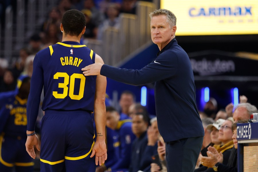 Golden State Warriors head coach Steve Kerr, right, greets Stephen Curry, left, who heads to the bench during the first half of an NBA basketball game against the San Antonio Spurs in San Francisco, Friday, March 31, 2023. (AP Photo/Jed Jacobsohn)