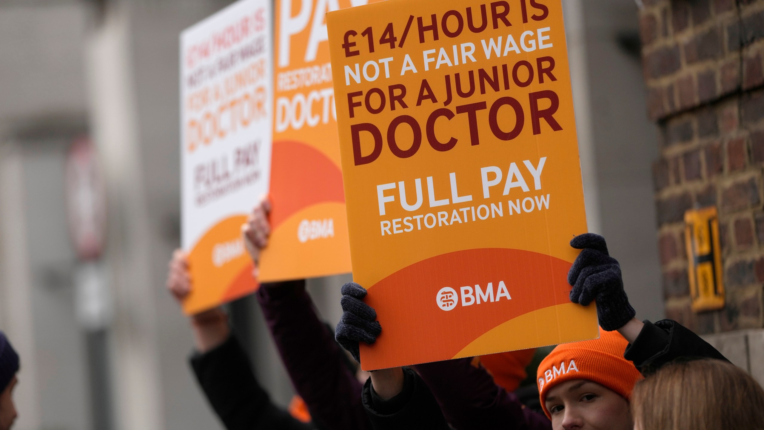 FILE - Junior doctors hold placards on a picket line outside St Mary's Hospital in London, Tuesday, March 14, 2023. A four-day strike planned by tens of thousands of doctors in England next week could lead to the postponement of a quarter-million medical appointments, a National Health Service official said Saturday, April 8, 2023. (AP Photo/Alastair Grant, File)