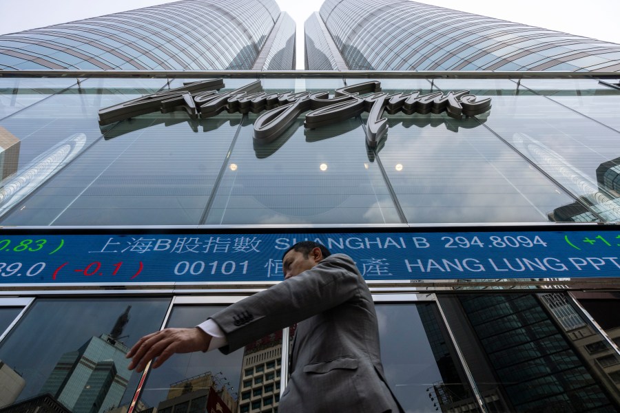 A pedestrian passes by the Hong Kong Stock Exchange electronic screen in Hong Kong, Wednesday, April 12, 2023. Asian shares were mostly higher Wednesday, as markets watched for key inflation data likely to influence the Federal Reserve's stance on interest rates. (AP Photo/Louise Delmotte)