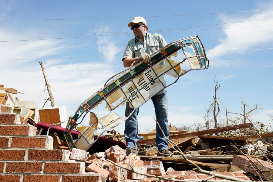 Charlie Weissinger carefully removes a stained glass window frame as he searches for his family's stained glass window in the rubble left from a March 24 tornado, that hit The Chapel of The Cross Episcopal Church in Rolling Fork, Miss., on March 29, 2023. The Weissinger family roots run deep in the 99-year old church and largely farming community and he expects his family will join members in rebuilding the church and repairing the family home which was damaged by the killer tornado. (AP Photo/Rogelio V. Solis)