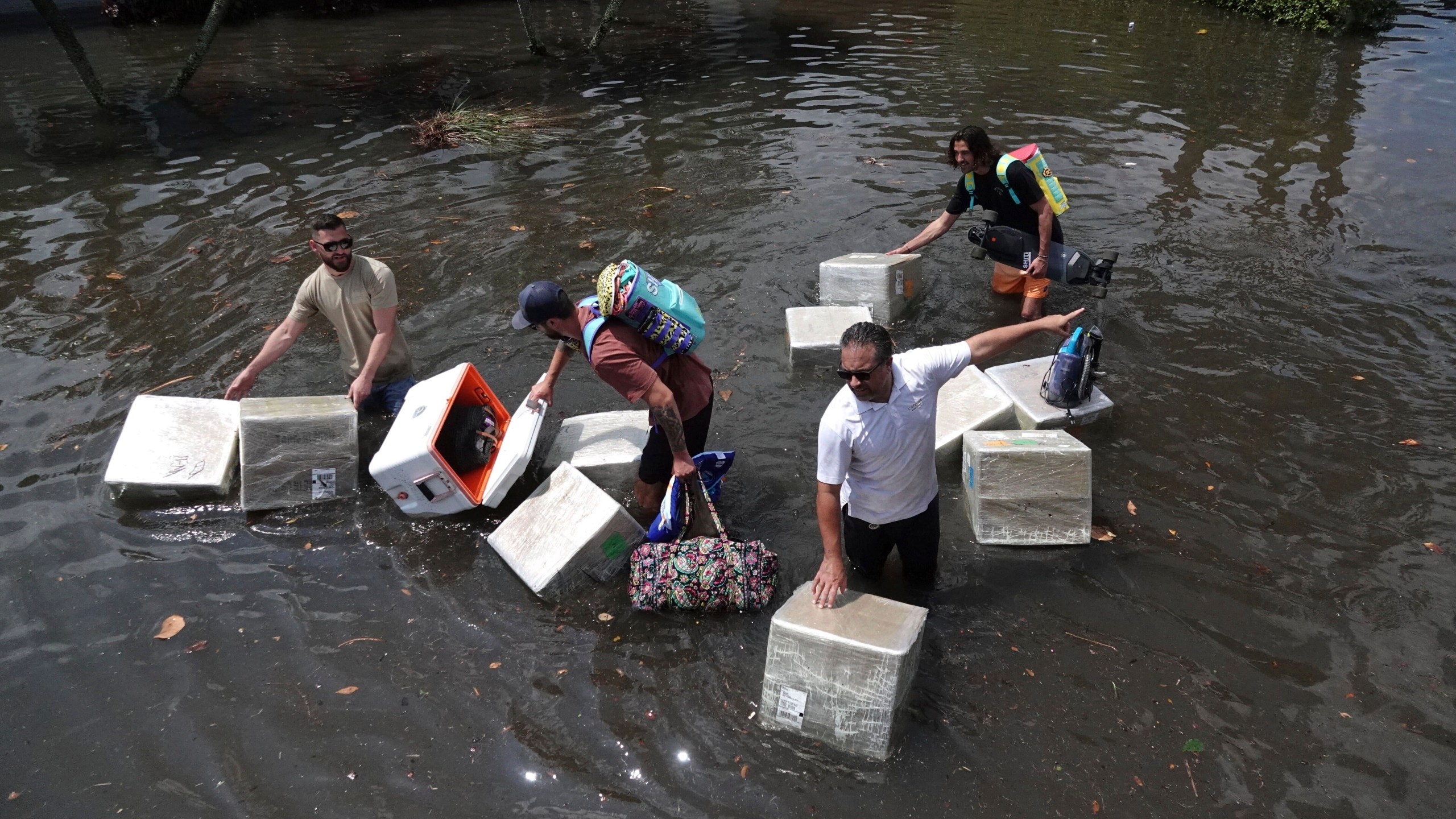 FILE - People try and save valuables as they wade through flood waters in the Edgewood neighborhood of Fort Lauderdale, Fla., April 13, 2023. Over 25 inches of rain fell in South Florida since Monday, causing widespread flooding. (Joe Cavaretta/South Florida Sun-Sentinel via AP)