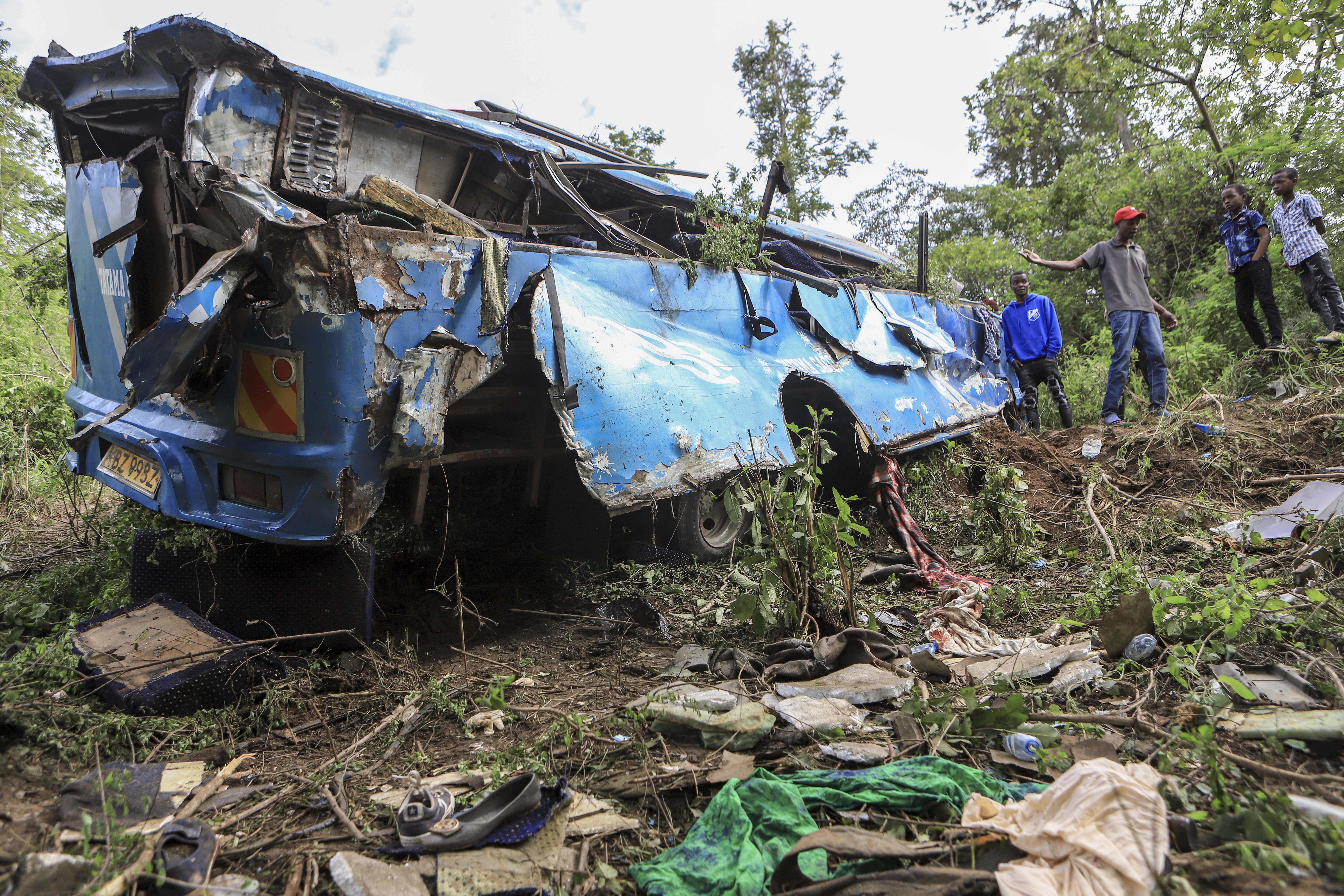 People observe the wreckage at the scene of a bus crash involving dozens of mourners who were returning from a funeral, near Mwatate, in southern Kenya, Sunday, April 16, 2023. At least 10 people died when the bus they were traveling in left the road and rolled several times in southern Kenya, police said Sunday. (AP Photo)