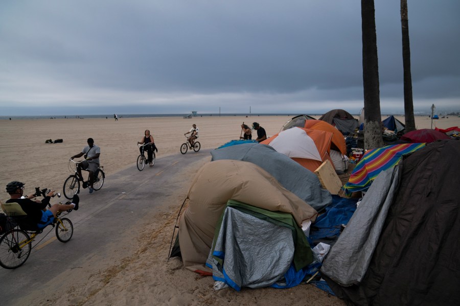 FILE - People ride their bikes past a homeless encampment set up along the boardwalk in the Venice neighborhood of Los Angeles on June 29, 2021. Democratic Mayor Karen Bass, who was elected in November 2023 after promising to take on the city’s out-of-control homeless crisis, announced Monday, April 17, she would recommend spending what she called a record $1.3 billion next year to get unhoused people into shelter and treatment programs. (AP Photo/Jae C. Hong, File)