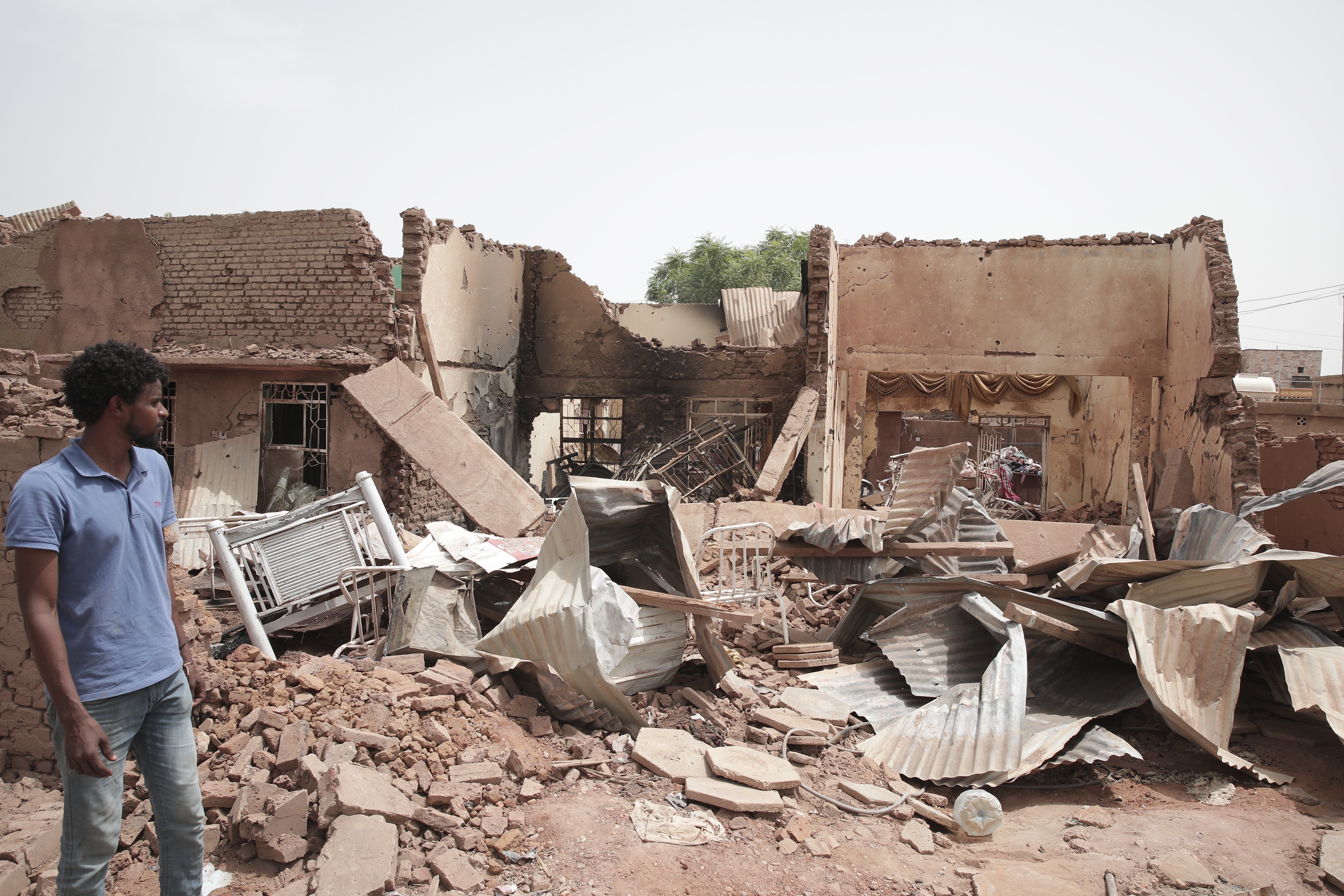 A man walks by a house hit in recent fighting in Khartoum, Sudan, Tuesday, April 25, 2023. Sudan's warring generals have pledged to observe a new three-day truce that was brokered by the United States and Saudi Arabia to try to pull Africa's third-largest nation from the abyss. (AP Photo/Marwan Ali)