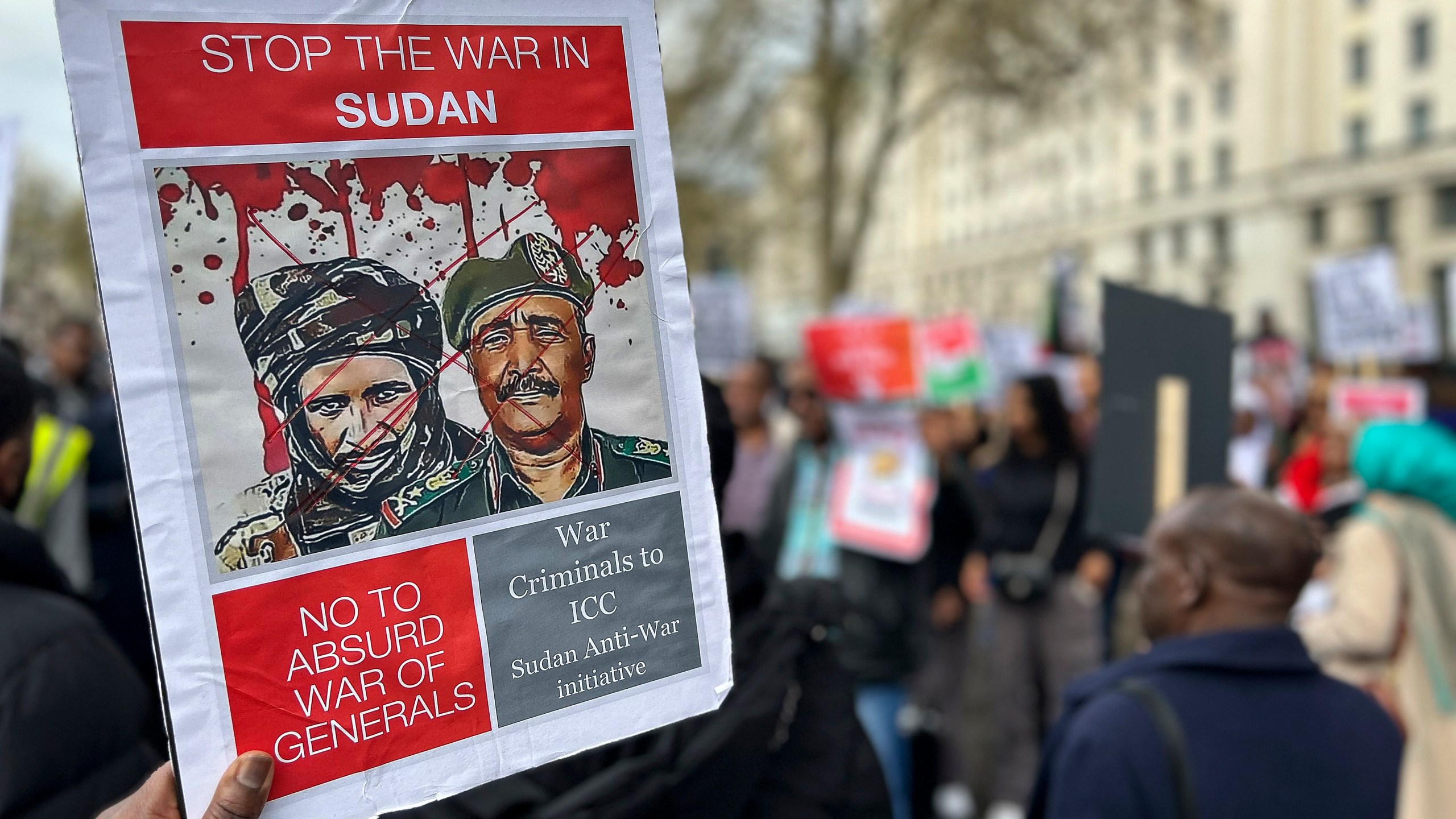 A demonstrator calling for the end of fighting in Sudan holds up a sign Sunday, April 23, 2023, outside Britain's Ministry of Defense in London. Sudanese emigrants living in the United Kingdom are worried about loved ones living in a battle zone back home and doing whatever they can to help in the dire situation.(AP Photo/Brian Melley)