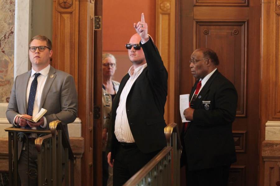 Kansas state Rep. Adam Thomas, R-Olathe, signals his vote in favor of overriding a veto from Gov. Laura Kelly of an anti-abortion bill from the back of the chamber, Wednesday, April 26, 2023, at the Statehouse in Topeka, Kansas. Thomas spent only brief moments in the chamber because a line drive hit him directly in the face while he was pitching during a recent softball game, resulting in serious injuries. (AP Photo/John Hanna)