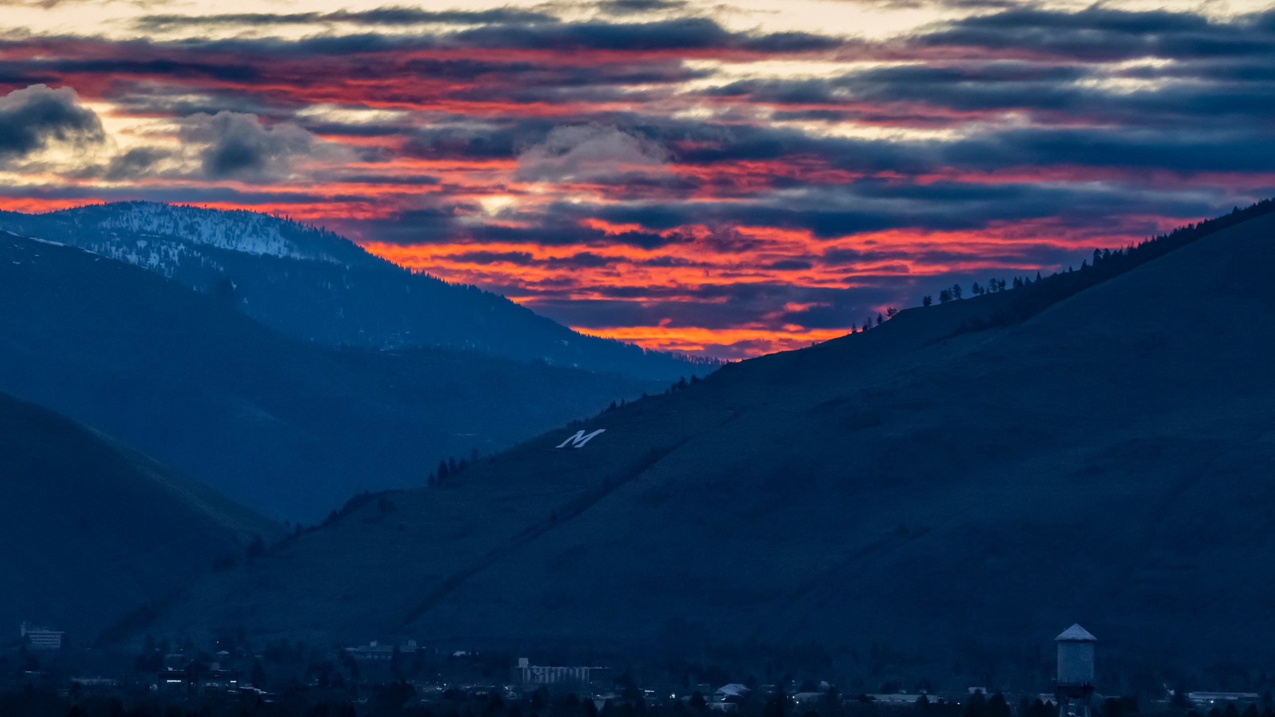 The sun rises beyond Mount Sentinel and downtown Missoula, Mont., Tuesday, April 25, 2023. It was little surprise that Missoula, a college town where pride flags are a common sight, sent Zooey Zephyr to the state legislature. Zephyr, the first openly transgender legislator in Montana’s history, was barred last week from speaking on the floor of the legislature by the Republican majority. (AP Photo/Tommy Martino)