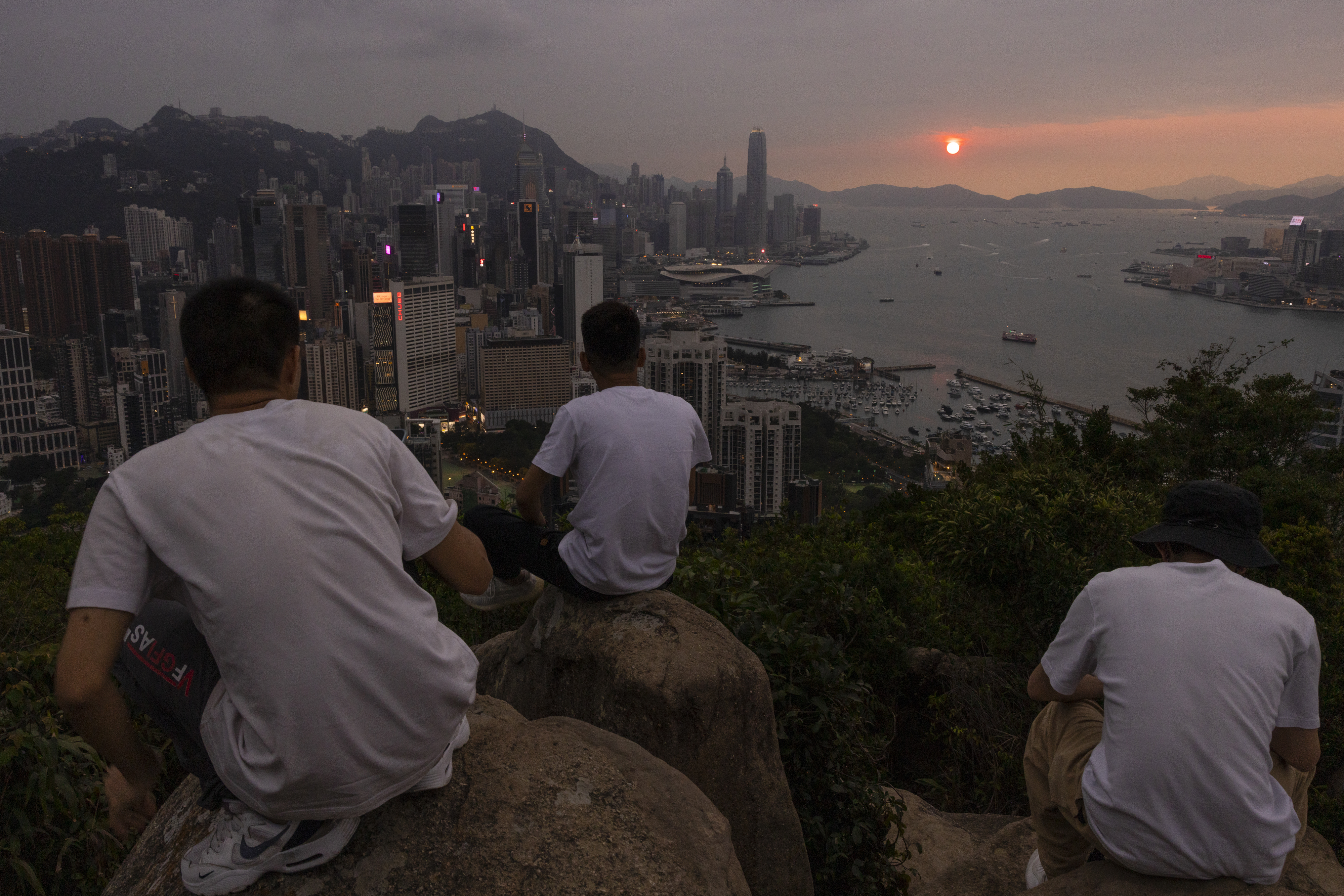 FILE - Mainland Chinese tourists look at sunset from a hill in Hong Kong, April 26, 2023. Living in Hong Kong today means juggling contradictory feelings. In 20 interviews, many said that when they focus on business indicators and everyday life, they see a recovery gathering pace after years of travel restrictions. But when it comes to anything political, the openness and freedoms that were once hallmarks of the Chinese-ruled former British colony seem permanently gone. (AP Photo/Louise Delmotte, File)