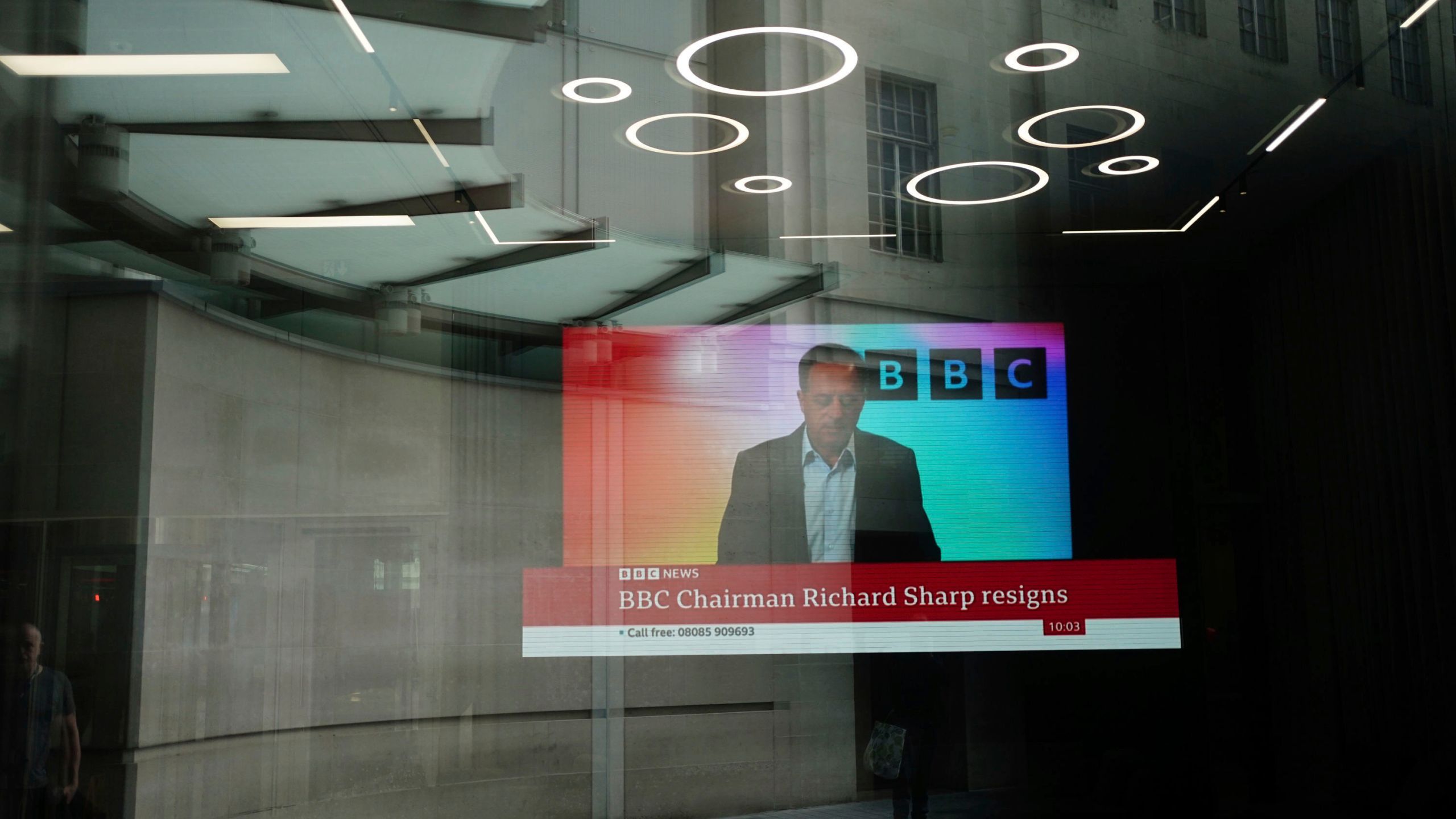 A screen showing a news report through the windows of the BBC, after chairman Richard Sharp announced he was quitting as BBC chairman, in London, Friday April 28, 2023. The chairman of the BBC has resigned after a report found he breached the government rules governing public appointments. The publicly funded national broadcaster has been under pressure after it was revealed that Sharp, a Conservative Party donor helped arrange a loan for then-Prime Minister Boris Johnson in 2021, weeks before he was appointed to the BBC post on the government’s recommendation. (Jordan Pettitt/PA via AP)