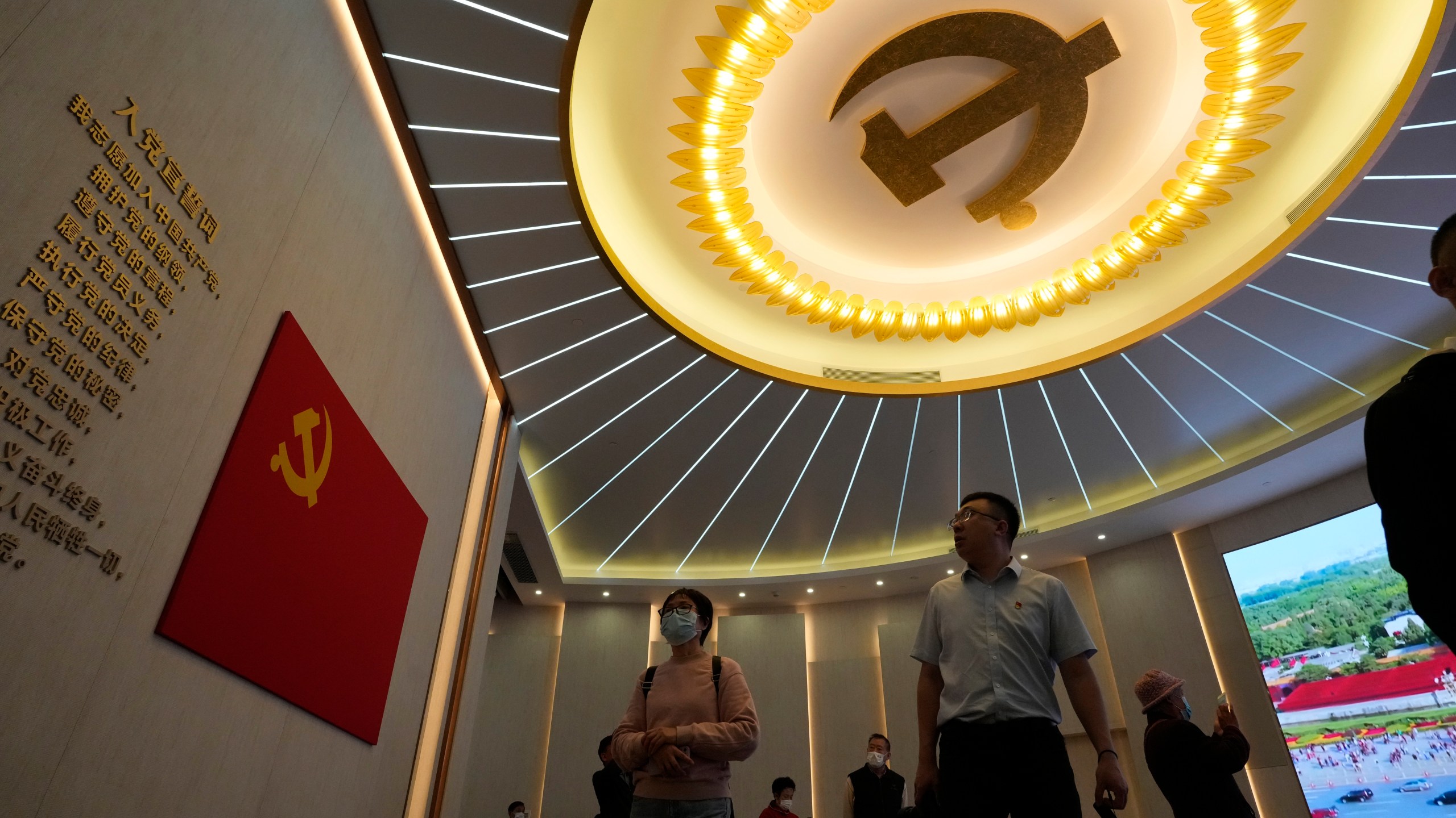 Visitors past near the emblems of the Chinese Communist Party at an exhibition in Shanghai, Thursday, April 20, 2023. Foreign companies are under growing pressure in China from anti-corruption, security and other investigations as President Xi Jinping's government tightens control over business, clashing with efforts to lure back investors after the pandemic. (AP Photo/Ng Han Guan)