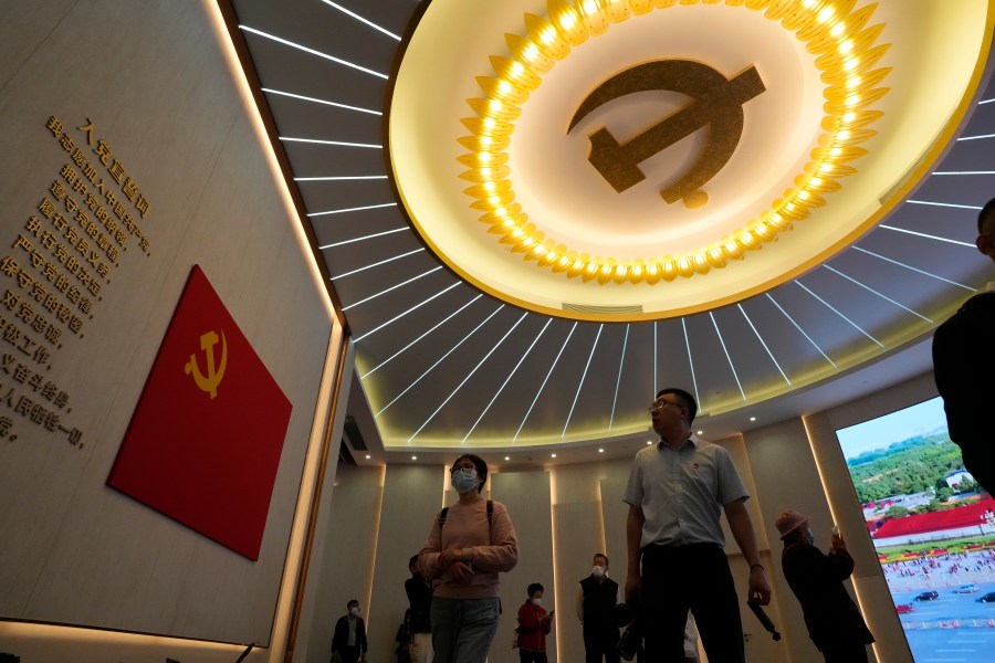 Visitors past near the emblems of the Chinese Communist Party at an exhibition in Shanghai, Thursday, April 20, 2023. Foreign companies are under growing pressure in China from anti-corruption, security and other investigations as President Xi Jinping's government tightens control over business, clashing with efforts to lure back investors after the pandemic. (AP Photo/Ng Han Guan)