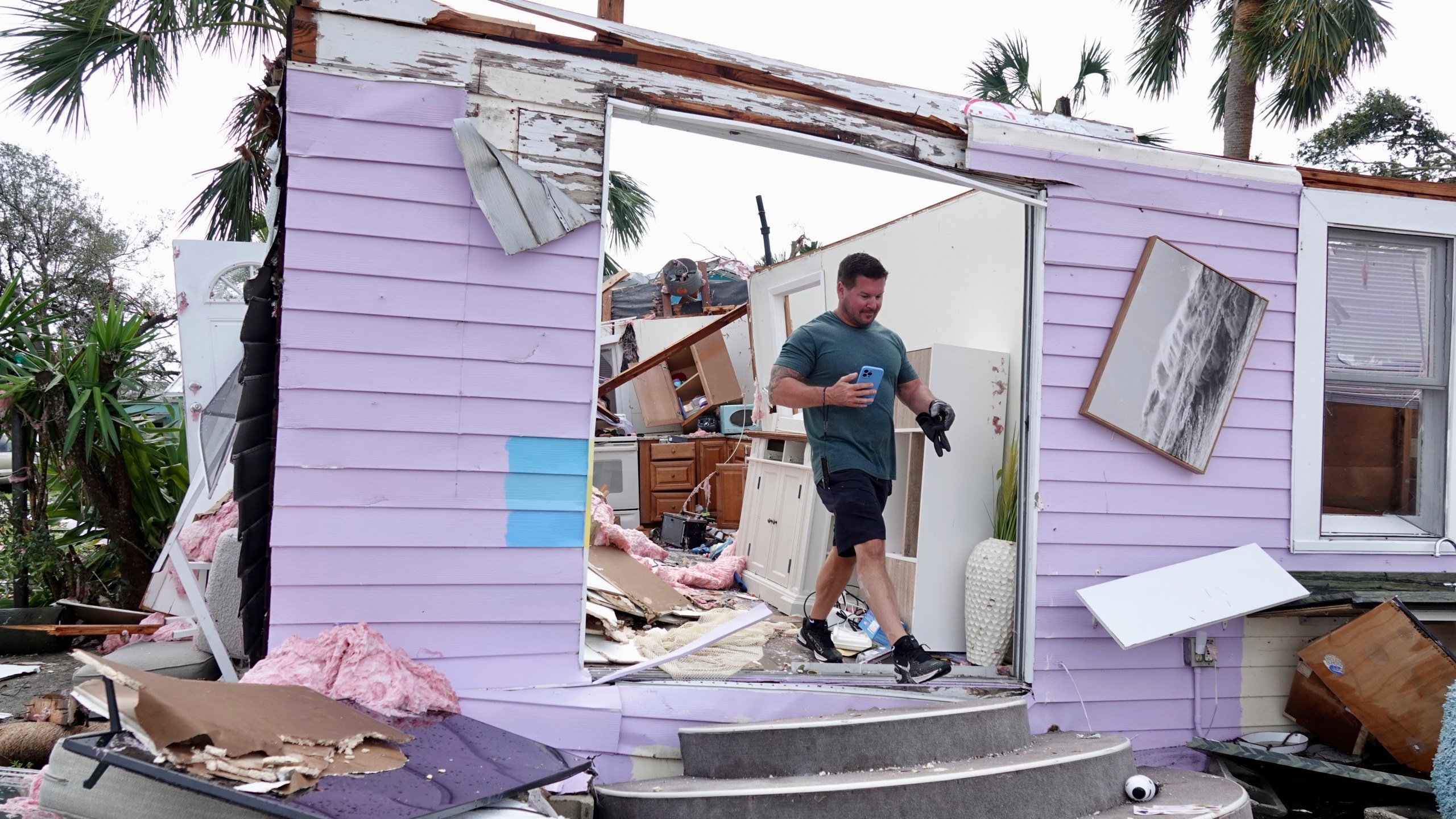 John Riendeau looks over damage to his rented bungalow on the intracoastal waterway, Sunday, April 30, 2023 in Palm Beach Gardens, Fla. A tornado touched down with 100 mph winds that overturned cars, snapped trees and damaged homes. The National Weather Service in Miami says the tornado hit late Saturday afternoon near Palm Beach Gardens Medical Center and headed northeast toward the coast. (Joe Cavaretta/South Florida Sun-Sentinel via AP)