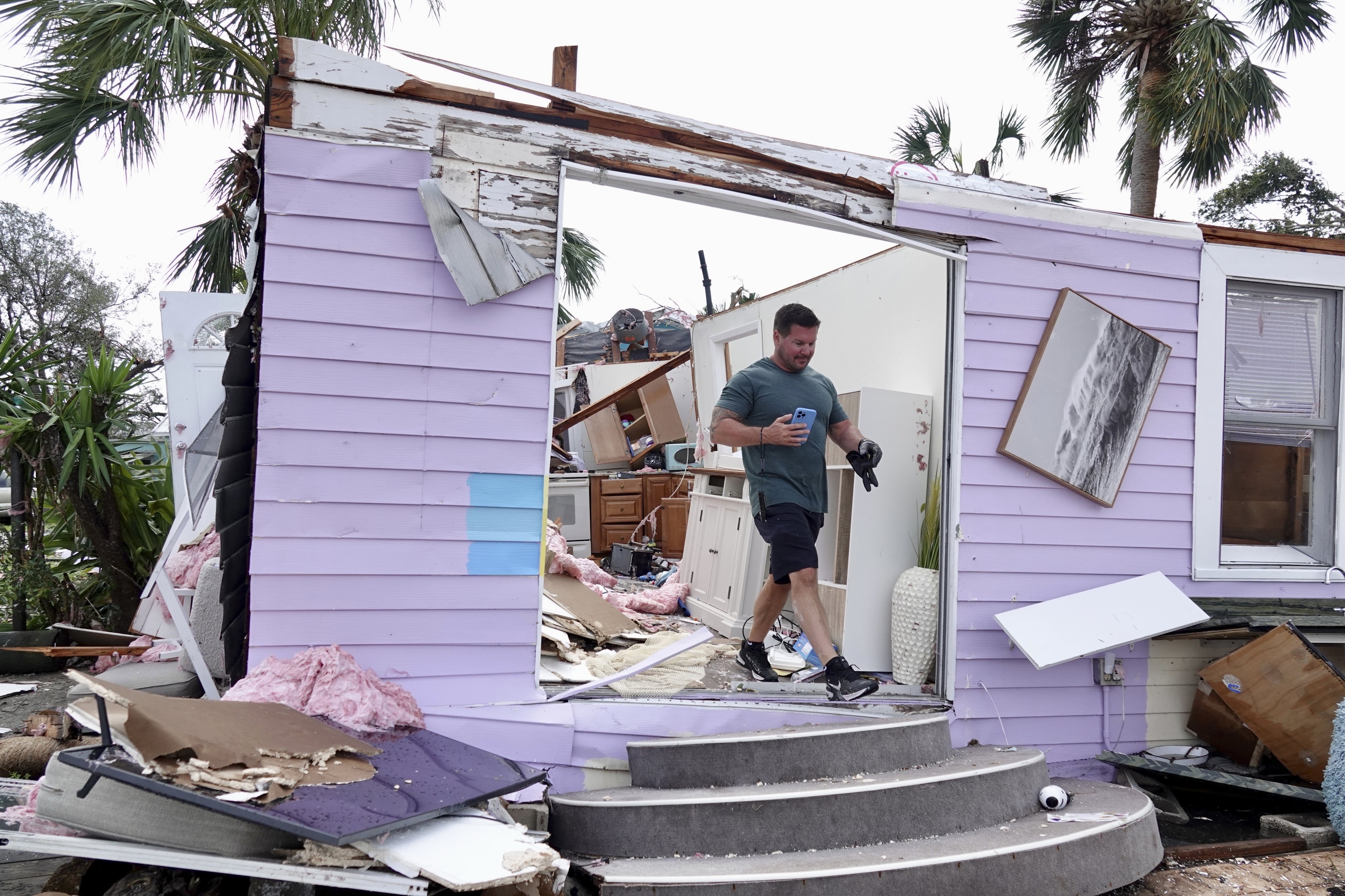 John Riendeau looks over damage to his rented bungalow on the intracoastal waterway, Sunday, April 30, 2023 in Palm Beach Gardens, Fla. A tornado touched down with 100 mph winds that overturned cars, snapped trees and damaged homes. The National Weather Service in Miami says the tornado hit late Saturday afternoon near Palm Beach Gardens Medical Center and headed northeast toward the coast. (Joe Cavaretta/South Florida Sun-Sentinel via AP)