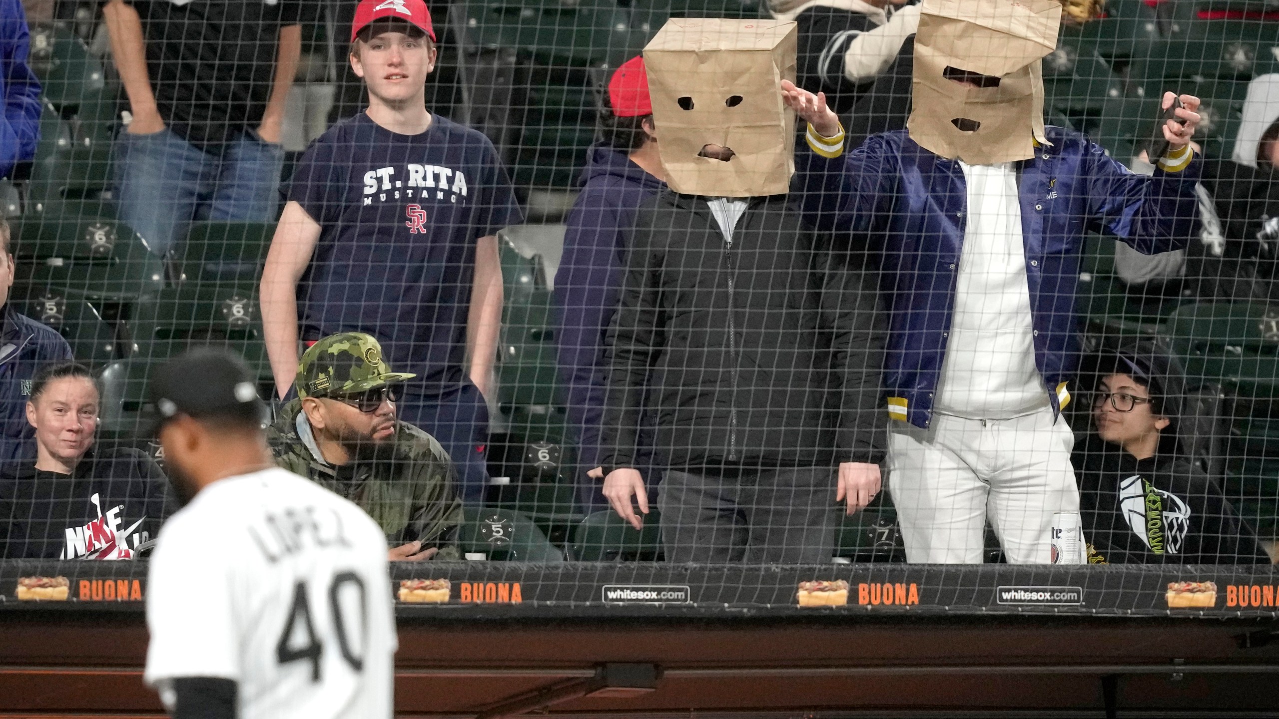 Two baseball fans wearing paper bags on their heads watch Chicago White Sox relief pitcher Reynaldo Lopez during the eighth inning of the team's baseball game against the Tampa Bay Rays on Thursday, April 27, 2023, in Chicago. (AP Photo/Charles Rex Arbogast)