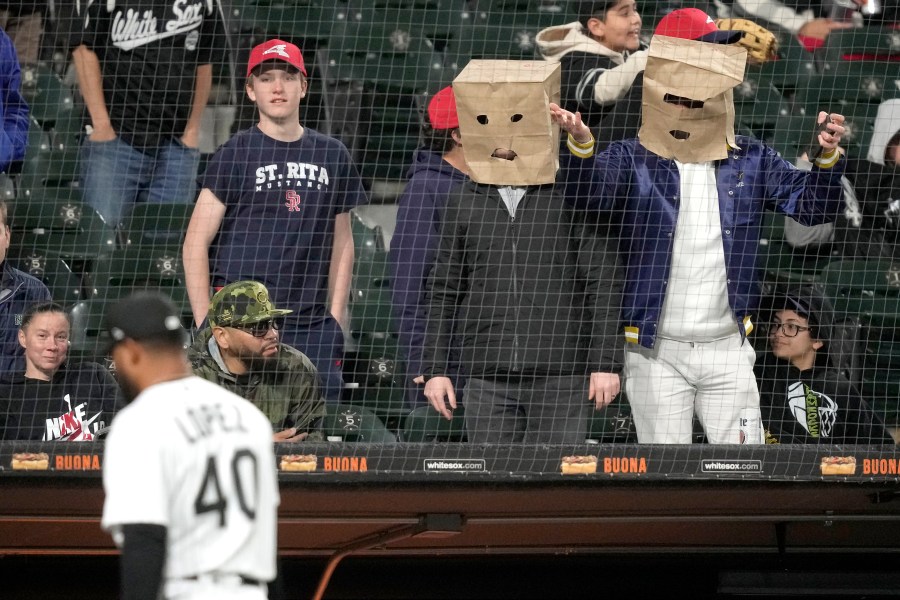 Two baseball fans wearing paper bags on their heads watch Chicago White Sox relief pitcher Reynaldo Lopez during the eighth inning of the team's baseball game against the Tampa Bay Rays on Thursday, April 27, 2023, in Chicago. (AP Photo/Charles Rex Arbogast)