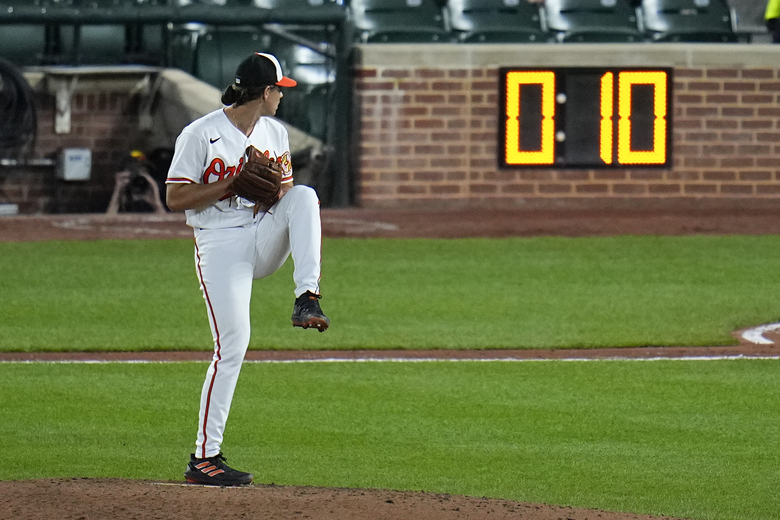 FILE - The pitch clock is visible as Baltimore Orioles starting pitcher Dean Kremer winds up to deliver during the sixth inning of a baseball game against the Boston Red Sox, April 24, 2023, in Baltimore, Md. Limits on infield shifts, a pitch clock and larger bases were implemented this year in an attempt to counter the impact of the Analytics Era suffocation of offense. (AP Photo/Julio Cortez, File)