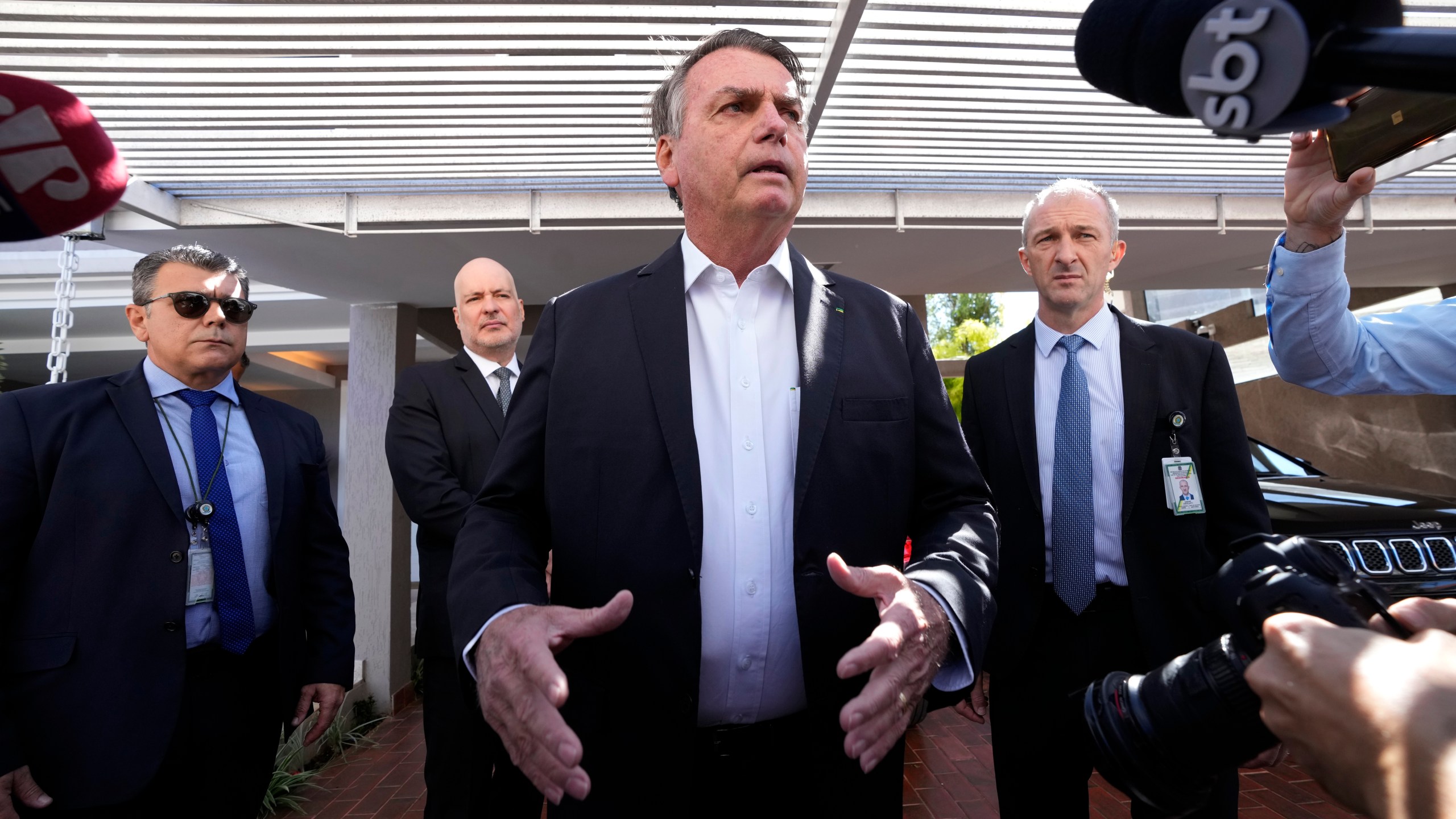 Former Brazilian President Jair Bolsonaro speaks to the press outside his home after Federal Police agents carried out a search and seizure warrant in Brasilia, Brazil, Wednesday, May 3, 2023. When asked about the search of Bolsonaro’s home in Brasilia, the Federal Police press office gave a statement saying officers were carrying out searches and arrests related to the introduction of fraudulent data related to the COVID-19 vaccine into the nation’s health system. (AP Photo/Eraldo Peres)