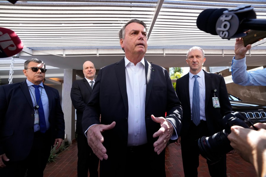 Former Brazilian President Jair Bolsonaro speaks to the press outside his home after Federal Police agents carried out a search and seizure warrant in Brasilia, Brazil, Wednesday, May 3, 2023. When asked about the search of Bolsonaro’s home in Brasilia, the Federal Police press office gave a statement saying officers were carrying out searches and arrests related to the introduction of fraudulent data related to the COVID-19 vaccine into the nation’s health system. (AP Photo/Eraldo Peres)