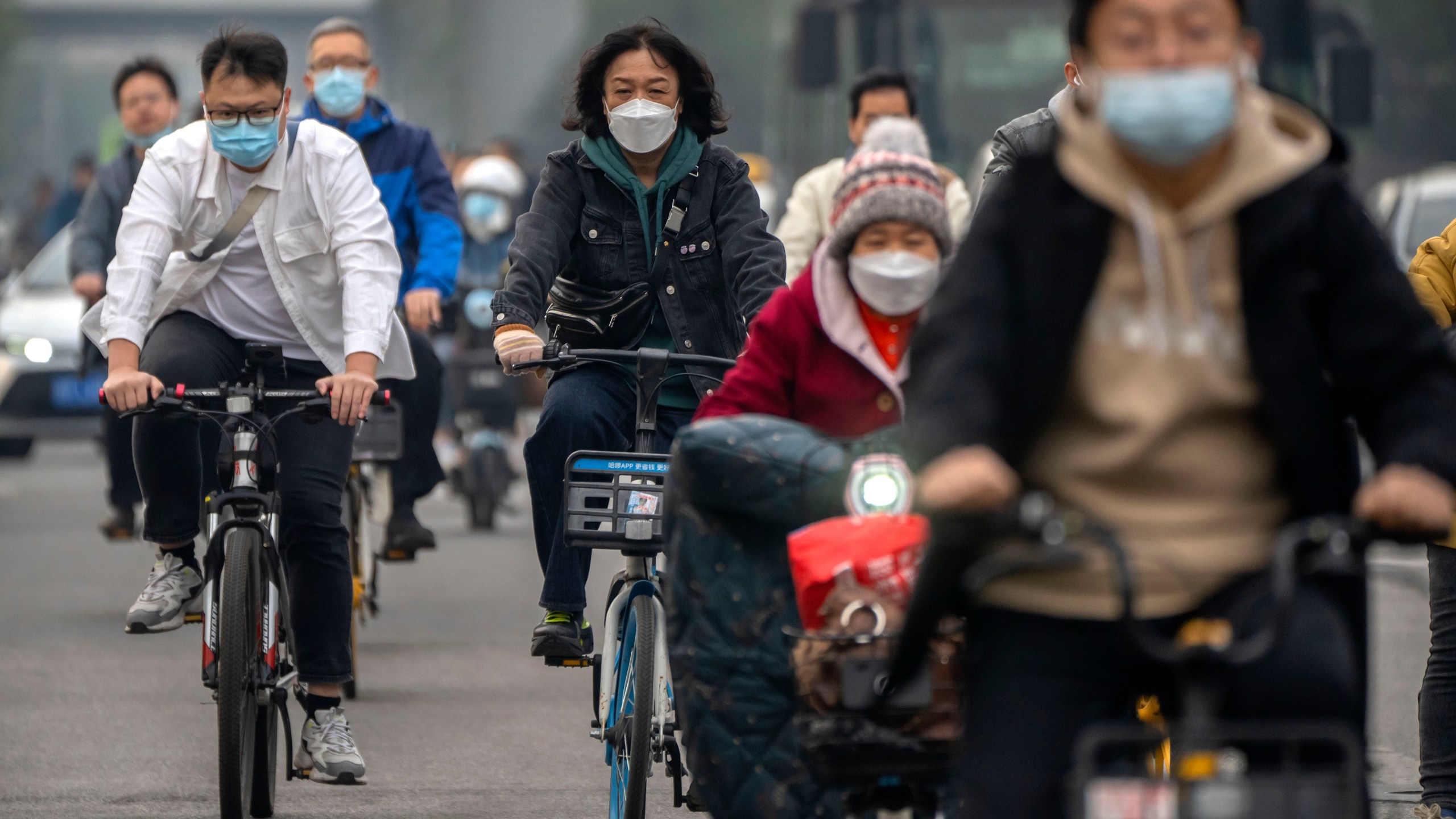 FILE - Commuters wearing face masks ride bicycles along a street in the central business district in Beijing, Thursday, Oct. 20, 2022. The World Health Organization downgraded its assessment of the coronavirus pandemic on Friday, May 5, 2023, saying it no longer qualifies as a global emergency. (AP Photo/Mark Schiefelbein, File)