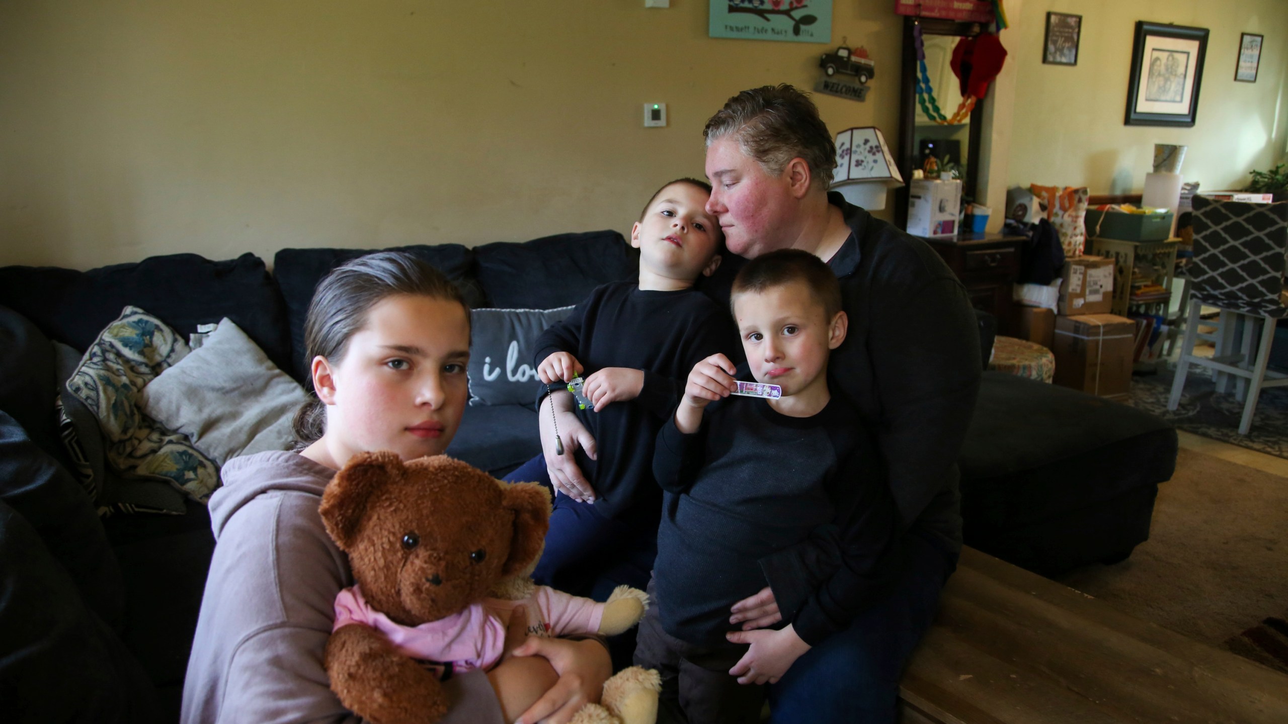 Jillian Philips sits with her children Macy, 10, and 4-year old twins, Emmett and Jude, right, in their home, Tuesday, May 2, 2023, in North Brookfield, Mass. Macy holds a teddy bear that houses a silver heart-shaped urn with some of the ashes of her deceased sister, Emilia, who died at 5 days old in 2015. Philips, who used the drug Mifepristone to manage her miscarriage, is concerned that other women who miscarry could suffer if the pill, also used for abortions, is taken off the market. (AP Photo/Reba Saldanha)