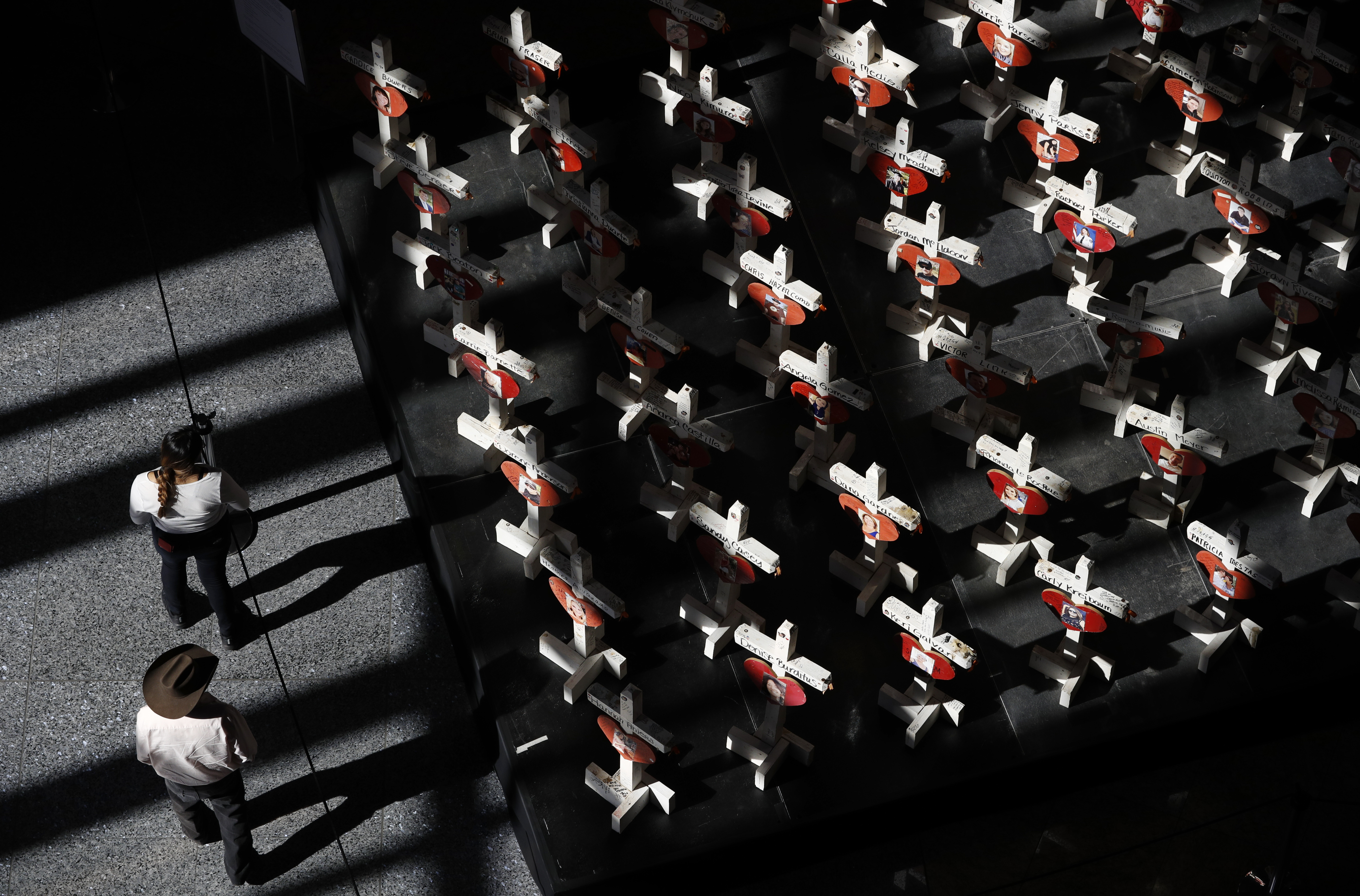 FILE - In this Sept. 25, 2018, photo, people look at a display of wooden crosses and a Star of David on display at the Clark County Government Center in Las Vegas. It was the deadliest mass shooting in modern U.S. history on the Las Vegas Strip in 2017. More than 100 people have been killed in mass shootings thus far in 2023, an average of one mass killing a week. (AP Photo/John Locher, File)