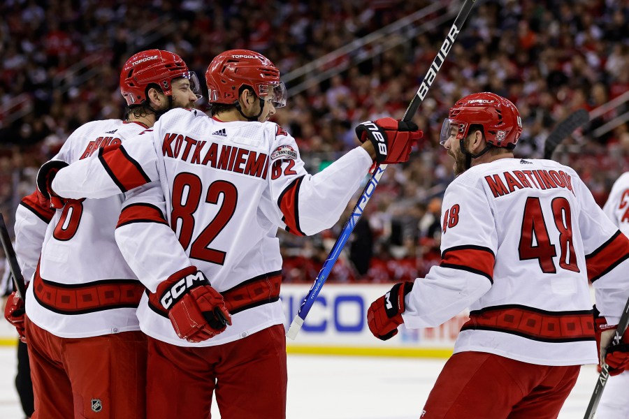 Carolina Hurricanes defenseman Brent Burns is congratulated by Jesperi Kotkaniemi (82) and Jordan Martinook (48) after scoring a goal against the New Jersey Devils during the second period of Game 4 of an NHL hockey Stanley Cup second-round playoff series Tuesday, May 9, 2023, in Newark, N.J. (AP Photo/Adam Hunger)