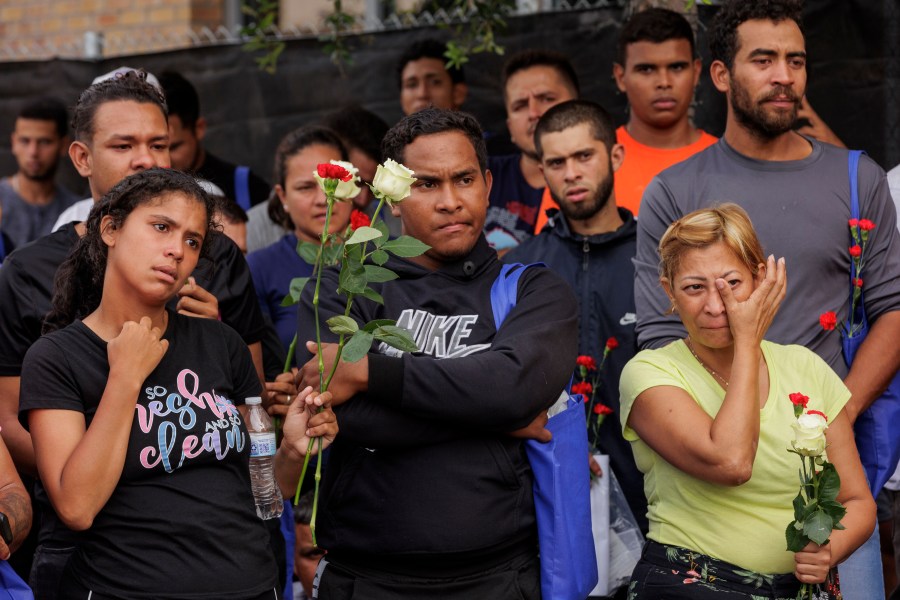 Migrants hold flowers and listen to speakers during a vigil for the eight migrants that were killed and several others that were injured the day before while waiting at a bus stop, in Brownsville, Texas, Monday, May 8, 2023. (AP Photo/Michael Gonzalez)