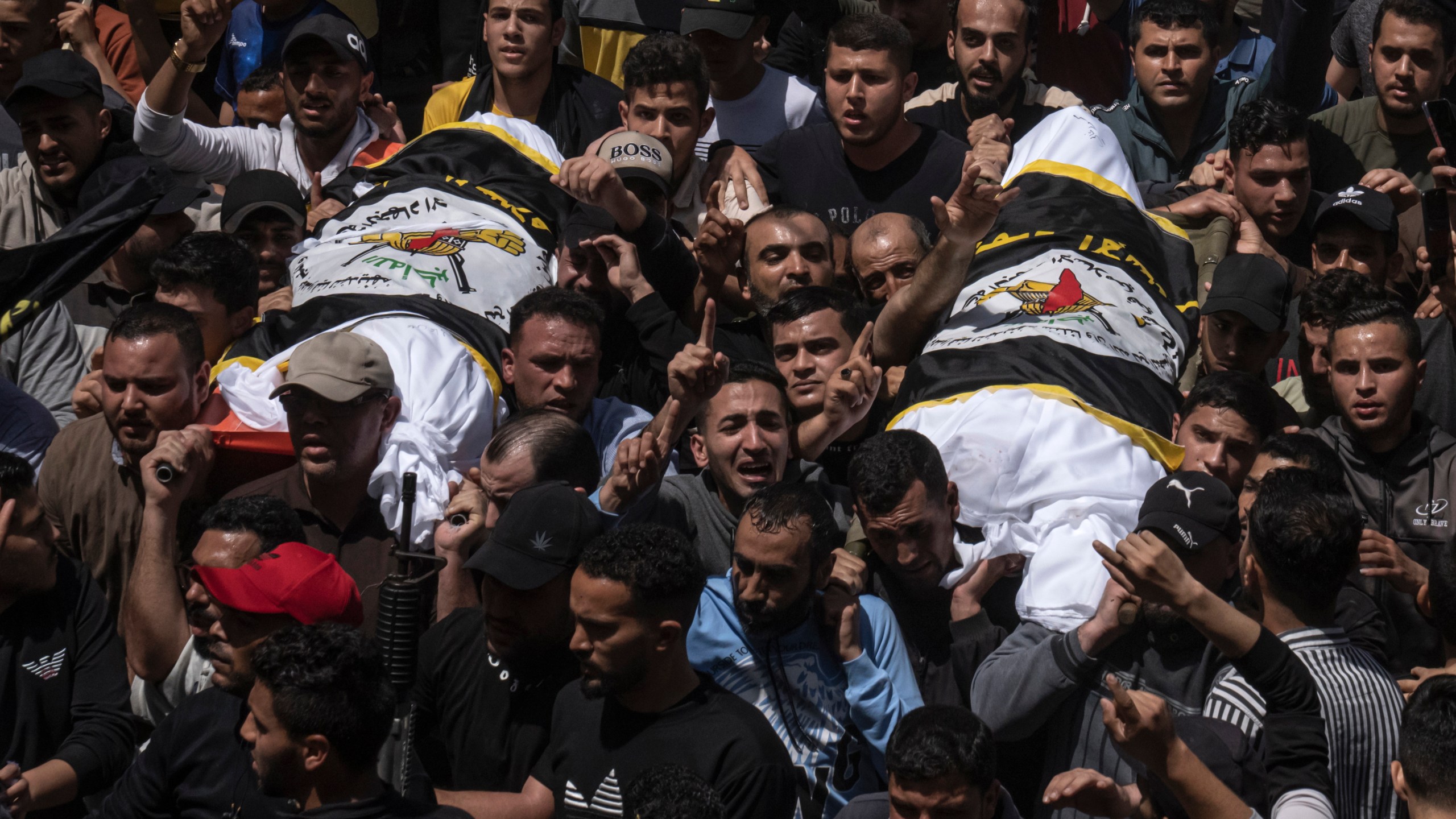 Palestinians carry the bodies of Islamic Jihad commander Ali Ghali, left, and his brother, Mohammed Ghali, both killed in an Israeli airstrike in Khan Younis, southern Gaza Strip, Thursday, May 11, 2023. They are both draped in the Islamic Jihad flag. (AP Photo/Fatima Shbair)