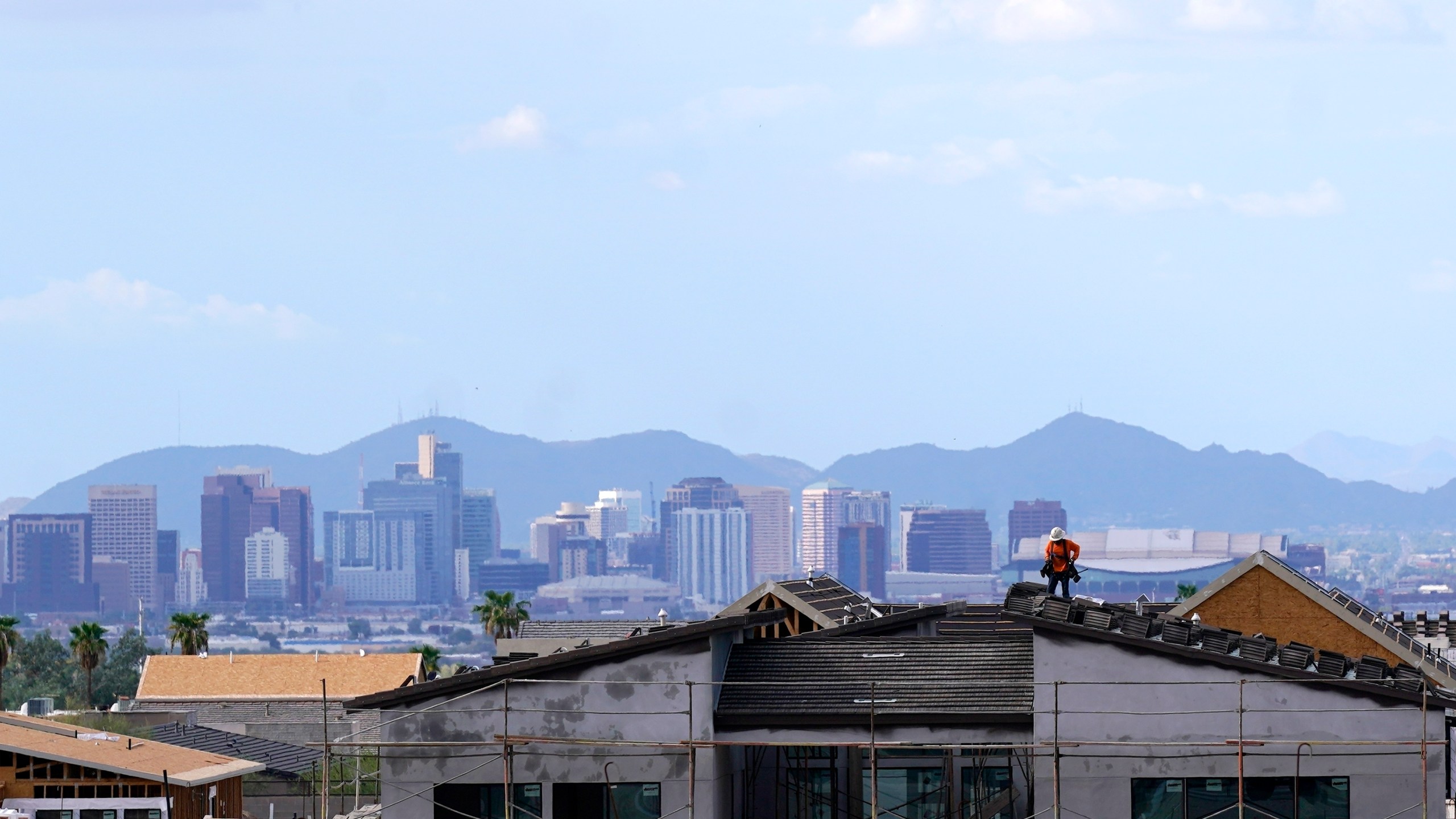 FILE - In this Aug. 12, 2021, file photo with the downtown skyline in the background, a roofer works on a new home being built in a new housing development as expansive urban sprawl continues in Phoenix. Some of the largest U.S. cities challenging their 2020 census numbers aren't getting the results they hoped for from the U.S. Census Bureau. (AP Photo/Ross D. Franklin, File)