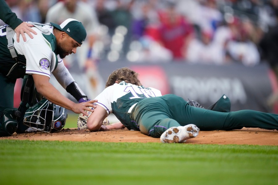 Colorado Rockies catcher Elias Diaz, left, checks on starting pitcher Ryan Feltner, who lies on the mound after getting hit by a single off the bat of Philadelphia Phillies' Nick Castellanos during the second inning of a baseball game Saturday, May 13, 2023, in Denver. (AP Photo/David Zalubowski)