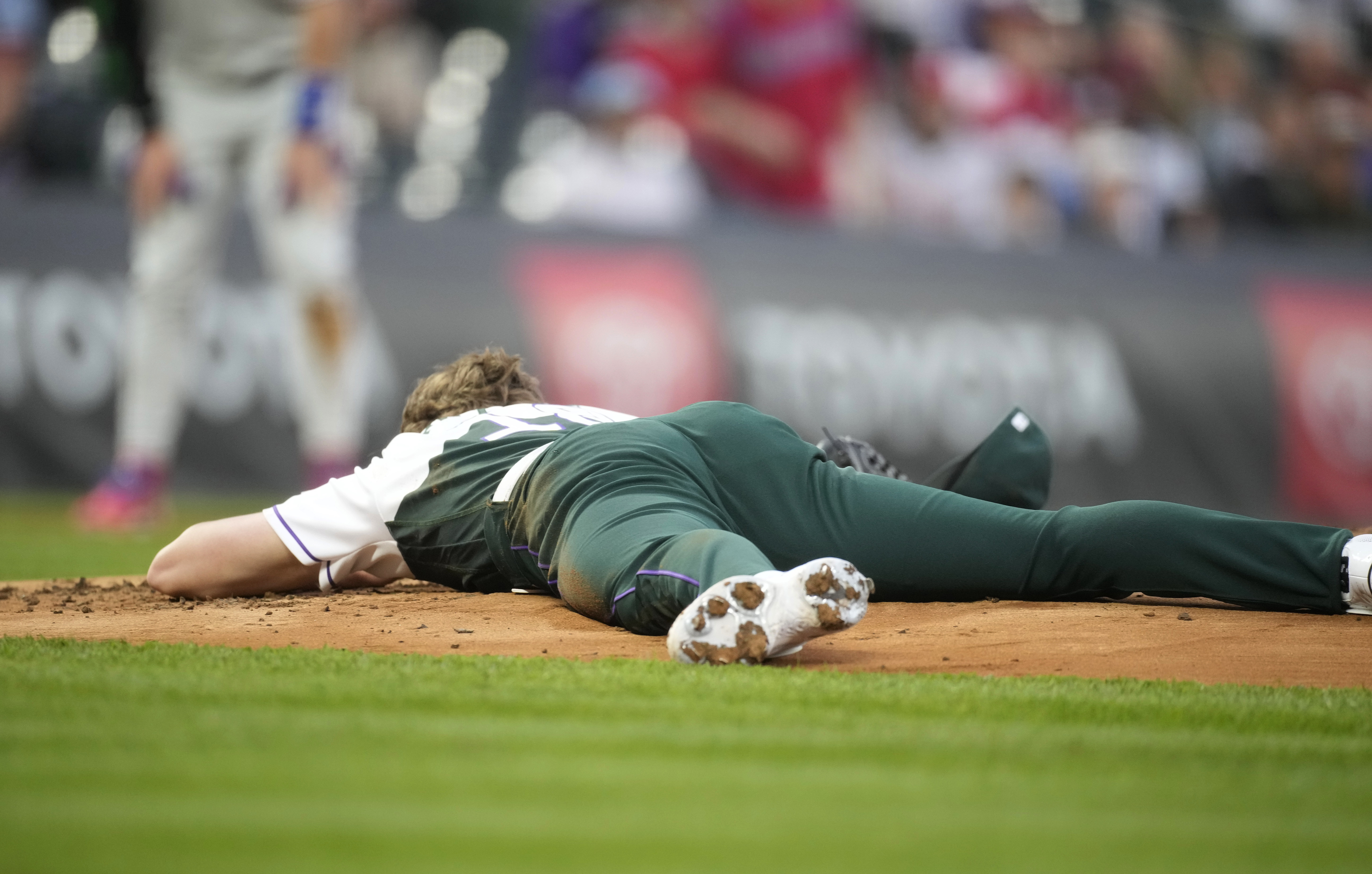 Colorado Rockies starting pitcher Ryan Feltner lies on the mound after getting hit by a single by Philadelphia Phillies' Nick Castellanos during the second inning of a baseball game Saturday, May 13, 2023, in Denver. (AP Photo/David Zalubowski)