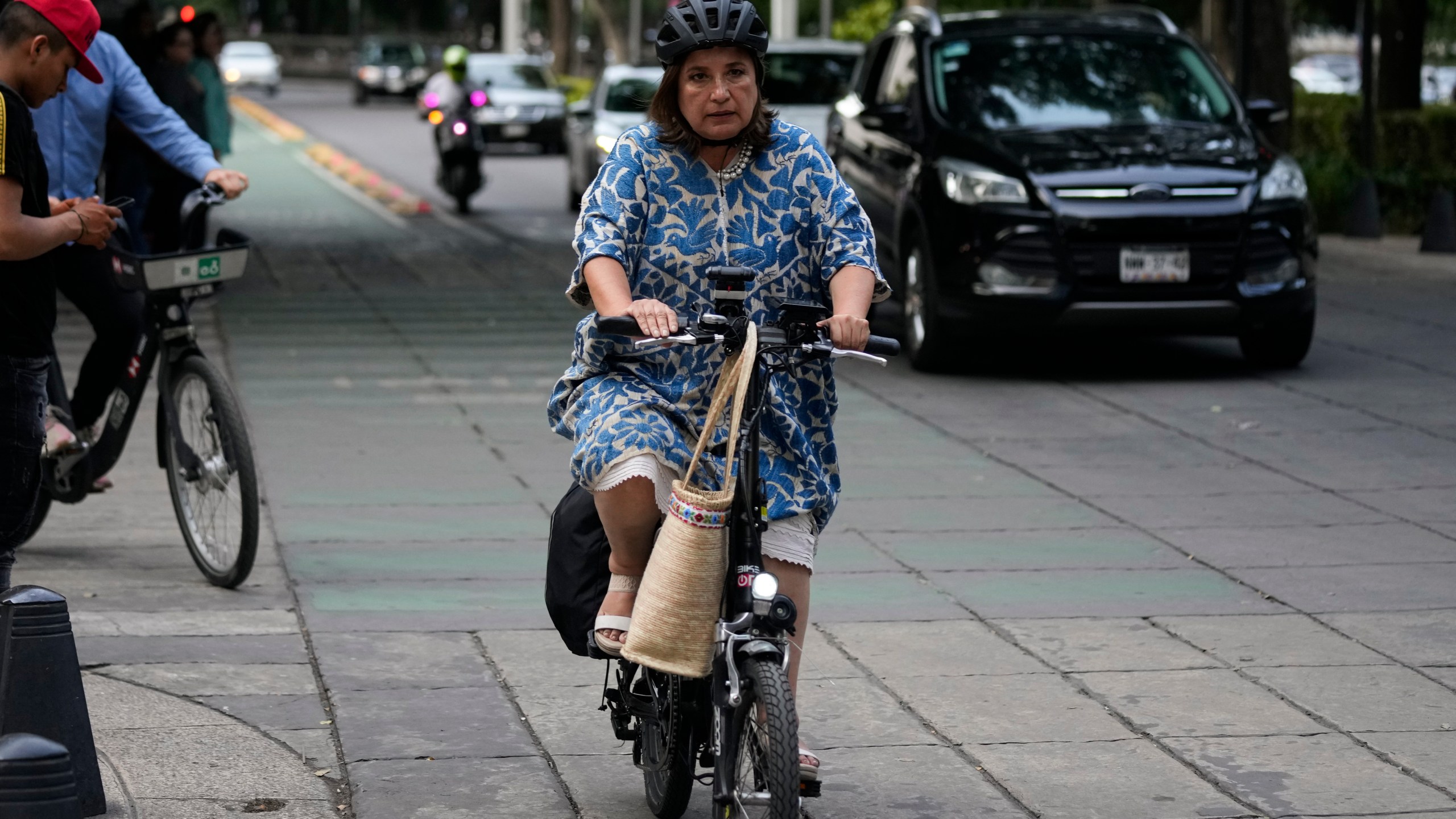 FILE - Senator Xochitl Galvez, an opposition presidential hopeful, rides a bike upon her arrival to a hotel for the announcement of the opposition presidential candidates in Mexico City, Wednesday, Aug. 9, 2023. The main opposition parties declared on Wednesday, August 30, 2023, Galvez as their virtual candidate for the upcoming presidential elections. (AP Photo/Fernando Llano, File)