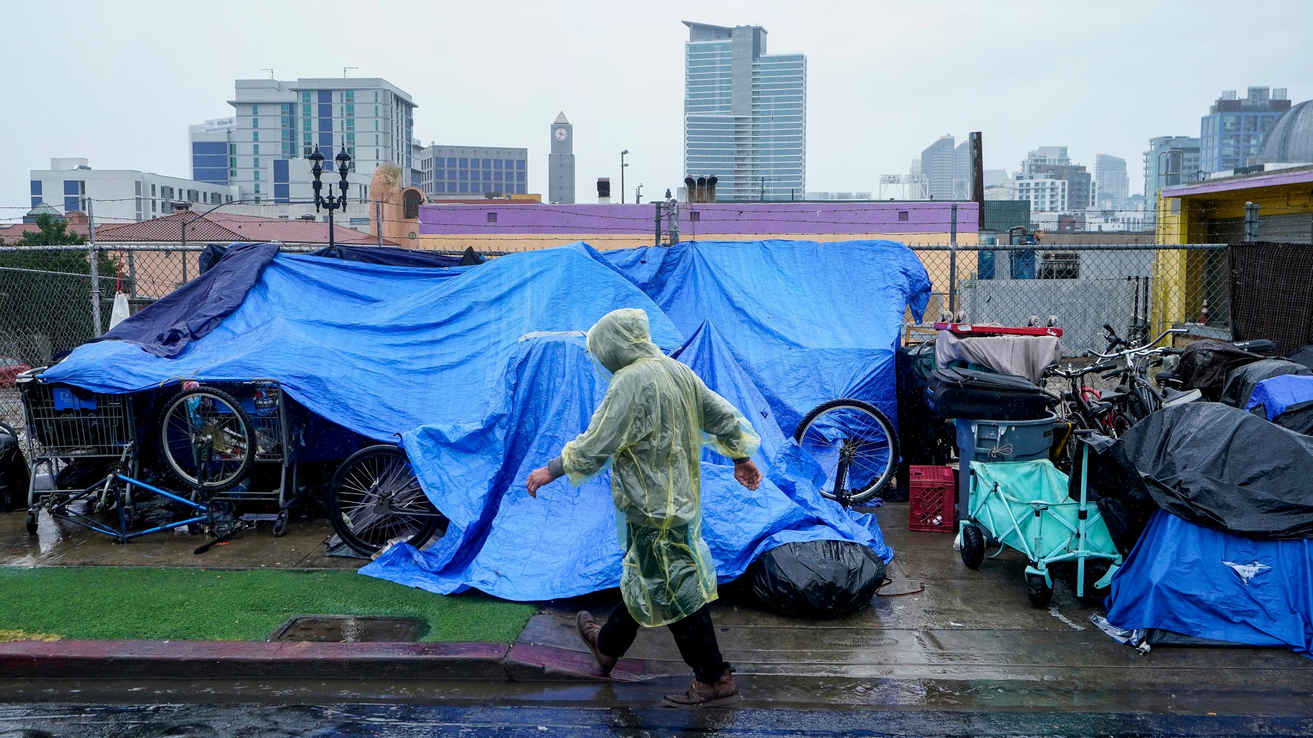 Homeless people use plastic tarps to shield themselves from a light rain brought by Tropical Storm Hilary in downtown San Diego, Sunday, Aug. 20, 2023. (AP Photo/Damian Dovarganes)