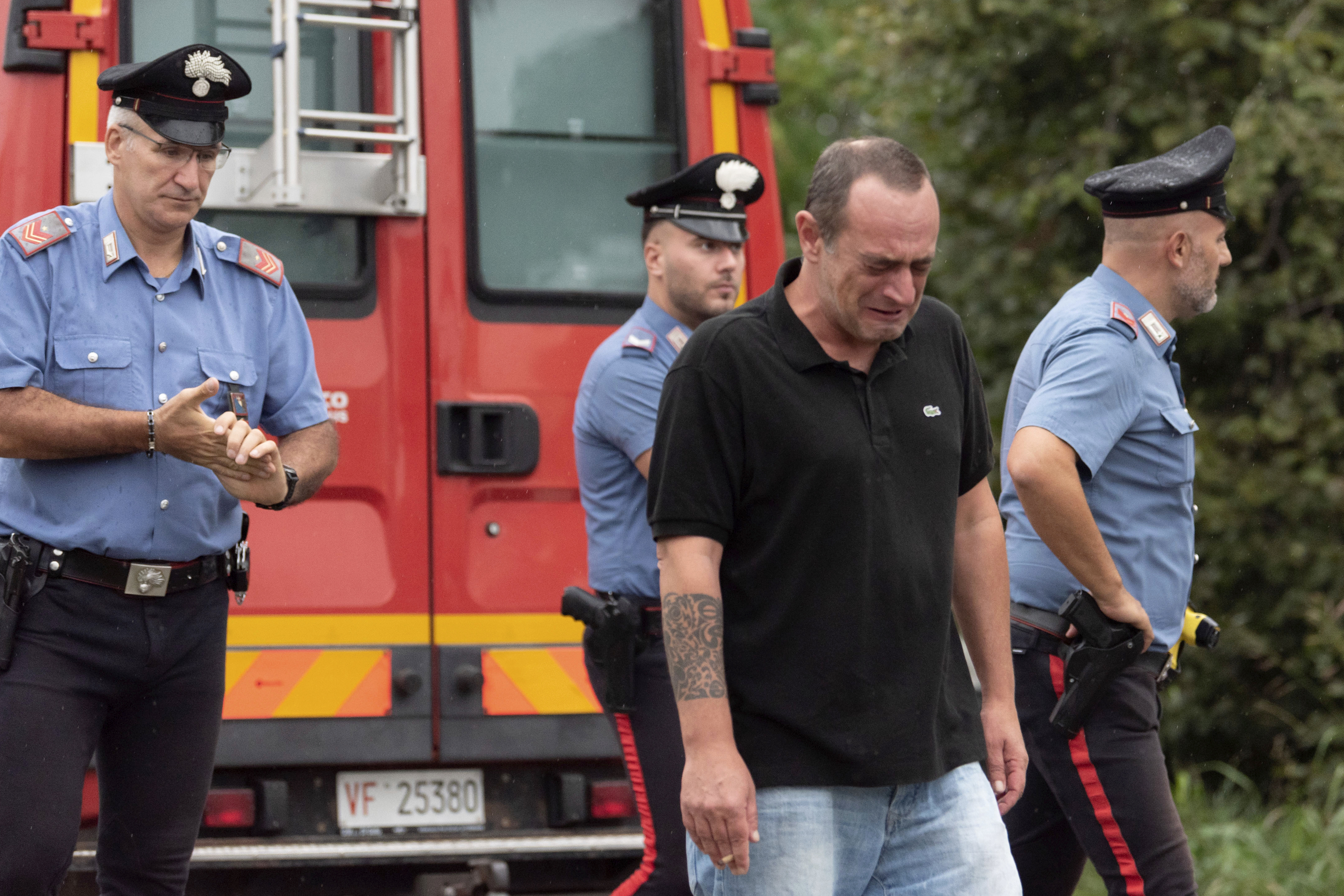 An unidentified man cries at the scene where an aircraft of the Italian acrobatic air team the Frecce Tricolori crashed during a practice run outside the northern city of Turin, Italy, Saturday, Sept. 16, 2023. The plane or parts of the plane reportedly struck a car carrying a family, killing a 5-year-old girl. A 9-year-old and the parents were being treated for burns, according to an Italian news agency. (Matteo Secci/LaPresse via AP)