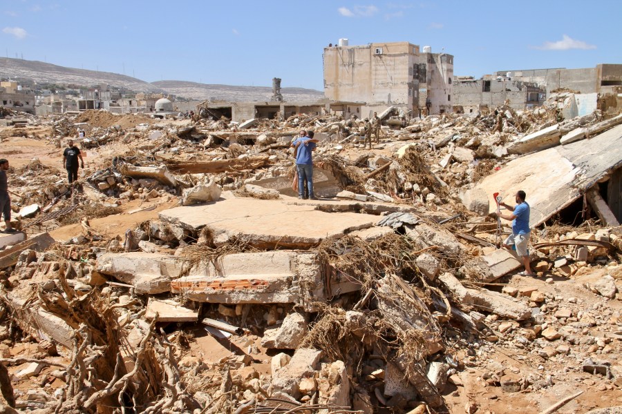 FILE - Two men hug as people look for survivors in the flooded city of Derna, Libya, Wednesday, Sept.13, 2023. For many Libyans, the disastrous flooding that killed more than 11,000 people have fostered a sense of unity. The collective grief has morphed into a rallying cry of national unity in a country blighted by 12 years of conflict and division. (AP Photo/Yousef Murad, File)