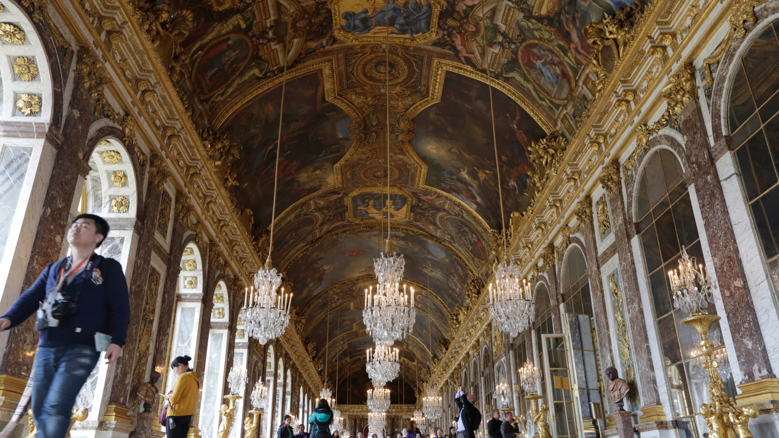 FILE - Visitors walk inside the Hall of Mirrors in the Versailles castle, on Nov. 17, 2015 in Versailles, west of Paris. France is rolling out the red carpet for King Charles III's state visit starting on Wednesday Sept. 20, 2023 at one of its most magnificent and emblematic monuments: the Palace of Versailles, which celebrates its 400th anniversary. (AP Photo/Amr Nabil, File)