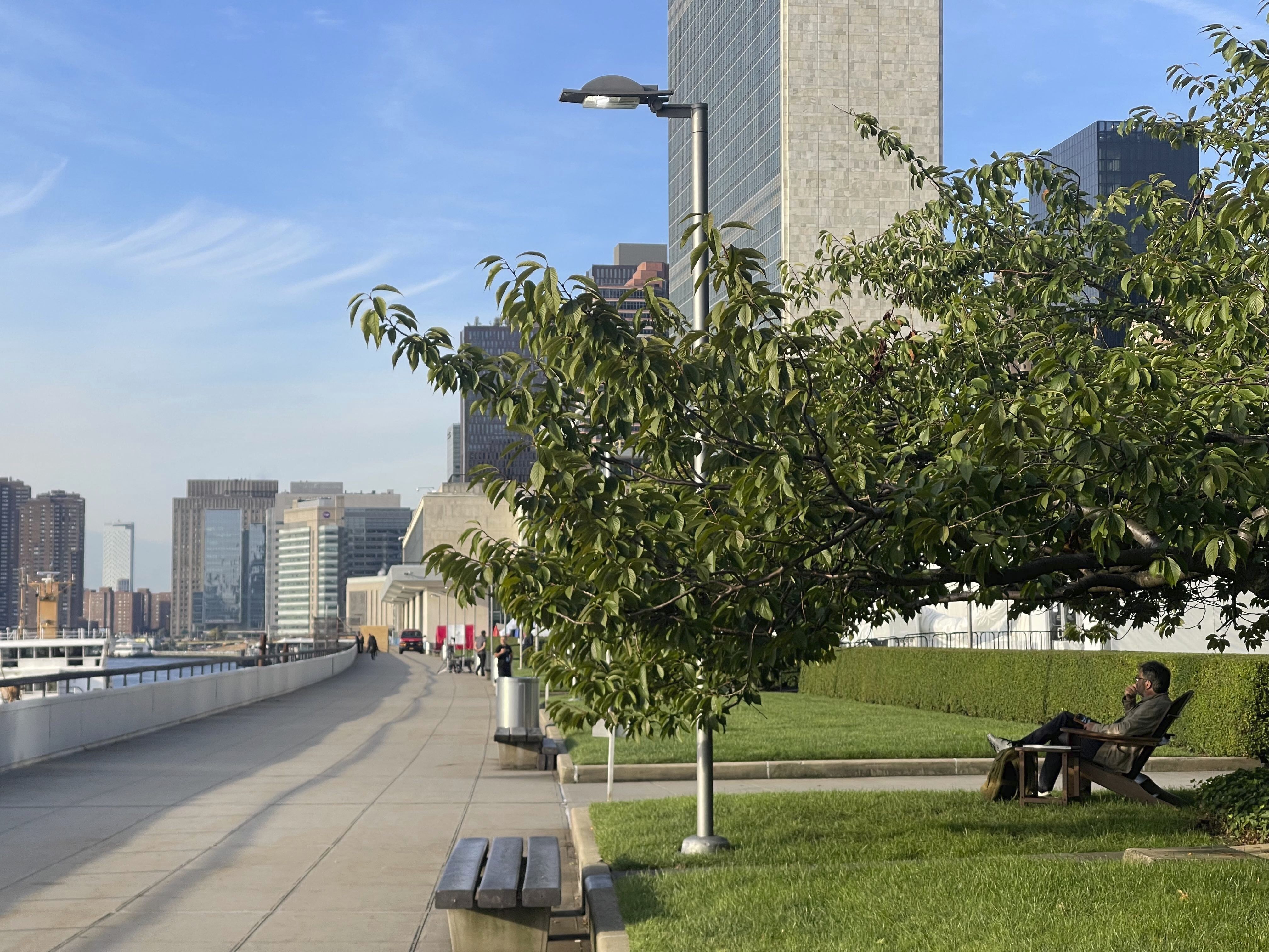 A man relaxes in a chair under a tree along the East River inside the U.N. compound in New York on Friday, Sept. 22, 2023. The parklet in the U.N. compound is a place where people go to find a few minutes of peace just yards from the buildings where leaders and diplomats deal with the world’s chaos. (AP Photo/Ted Anthony)