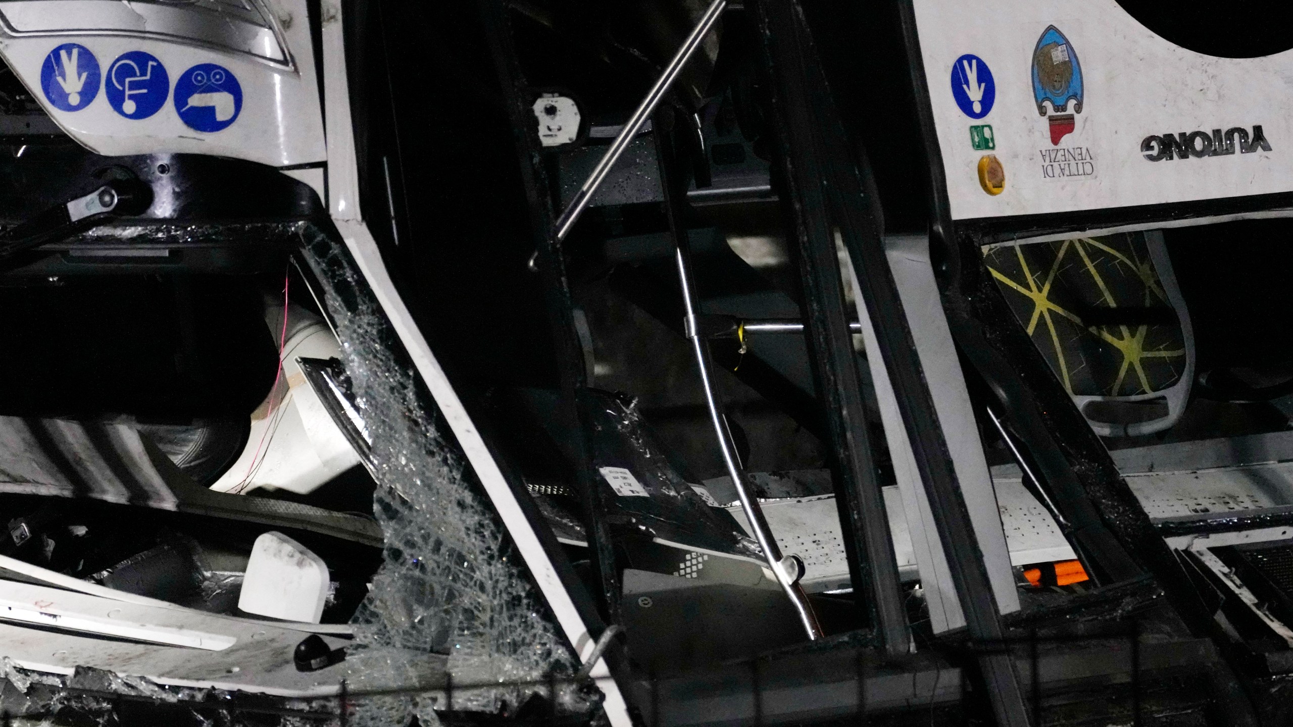 Italian firefighters work at the scene of a passenger bus accident in Mestre, near the city of Venice, Italy, Wednesday, Oct. 4, 2023. The bus fell from an elevated road, late Tuesday, killing multiple people. (AP Photo/Antonio Calanni)