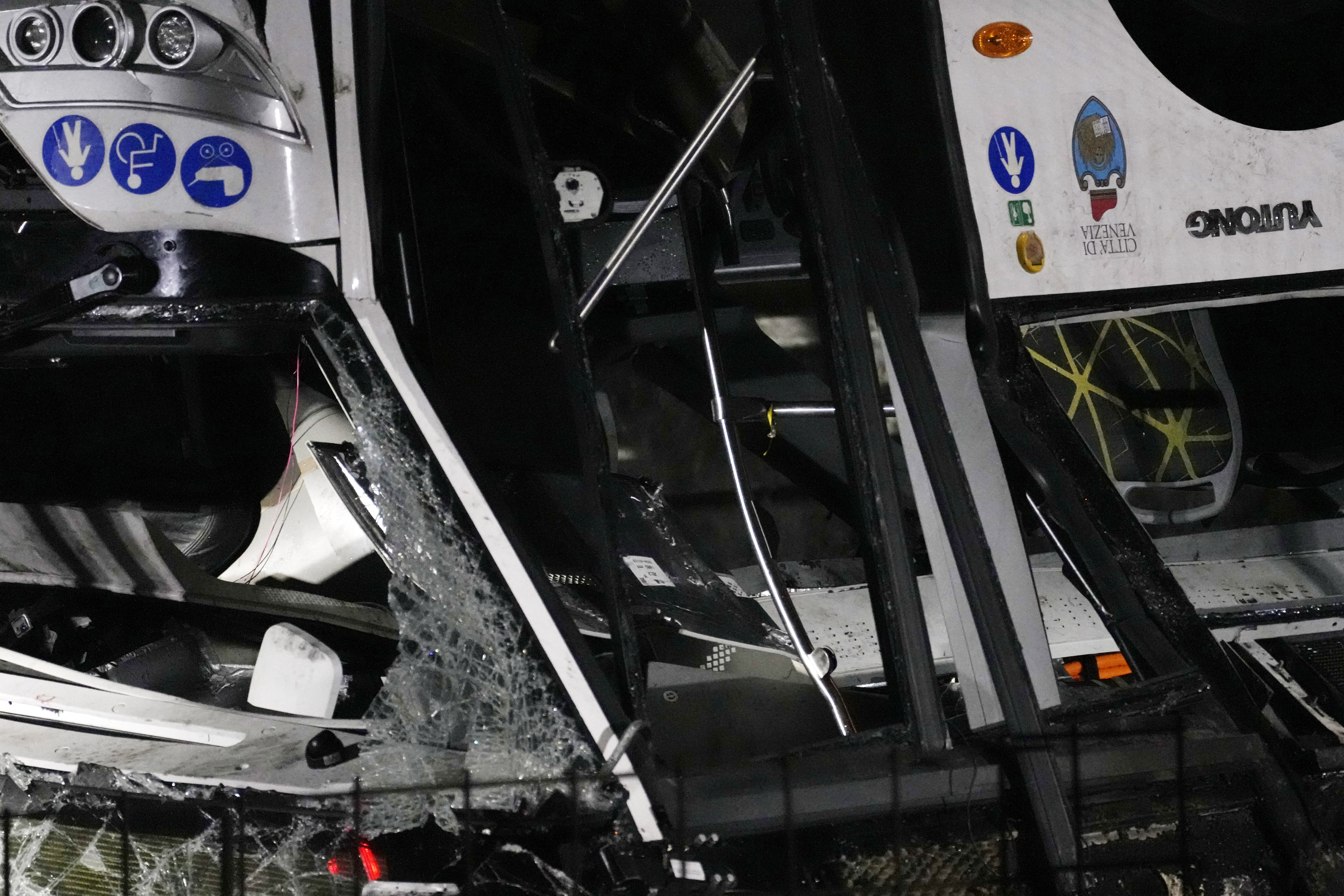 Italian firefighters work at the scene of a passenger bus accident in Mestre, near the city of Venice, Italy, Wednesday, Oct. 4, 2023. The bus fell from an elevated road, late Tuesday, killing multiple people. (AP Photo/Antonio Calanni)