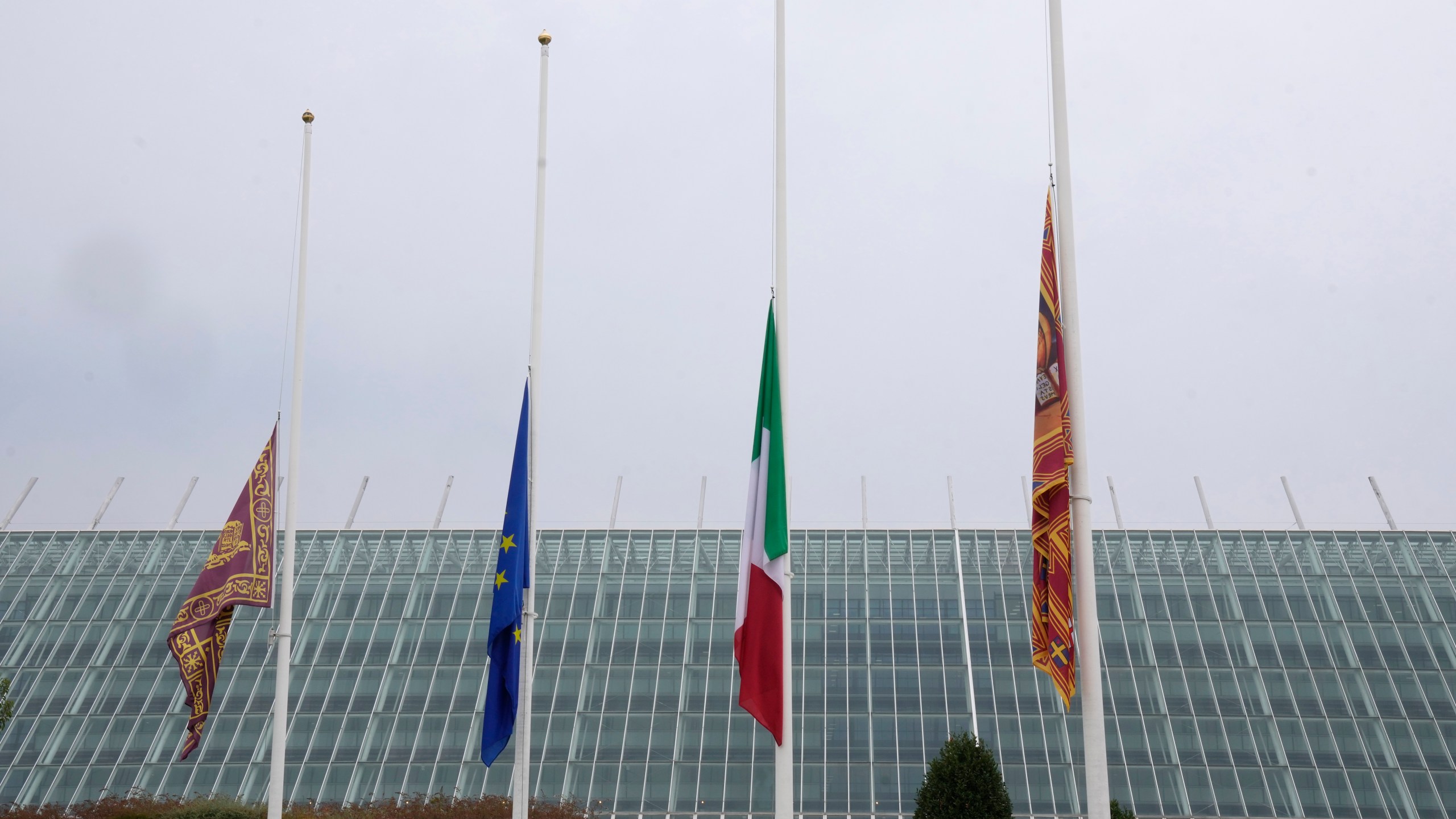 Flags at half mast are seen outside the Dell'Angelo hospital where the bus injured passengers are hospitalised after an accident in Mestre, near the city of Venice, Italy, Wednesday, Oct. 4, 2023. The bus fell from an elevated road, late Tuesday, killing multiple people. (AP Photo/Antonio Calanni)