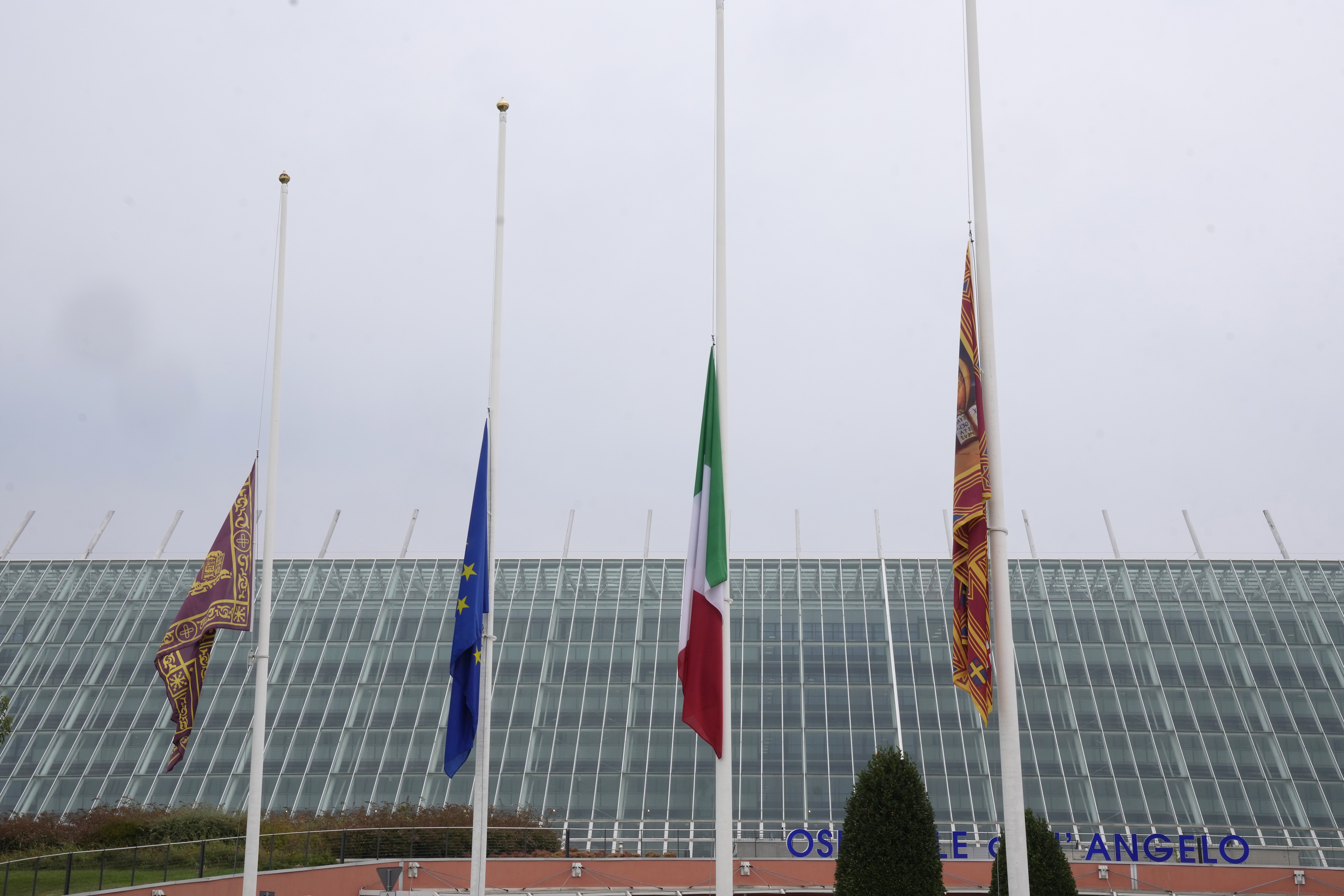 Flags at half mast are seen outside the Dell'Angelo hospital where the bus injured passengers are hospitalised after an accident in Mestre, near the city of Venice, Italy, Wednesday, Oct. 4, 2023. The bus fell from an elevated road, late Tuesday, killing multiple people. (AP Photo/Antonio Calanni)