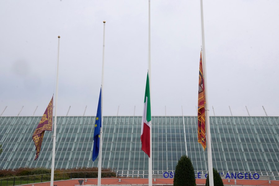 Flags at half mast are seen outside the Dell'Angelo hospital where the bus injured passengers are hospitalised after an accident in Mestre, near the city of Venice, Italy, Wednesday, Oct. 4, 2023. The bus fell from an elevated road, late Tuesday, killing multiple people. (AP Photo/Antonio Calanni)