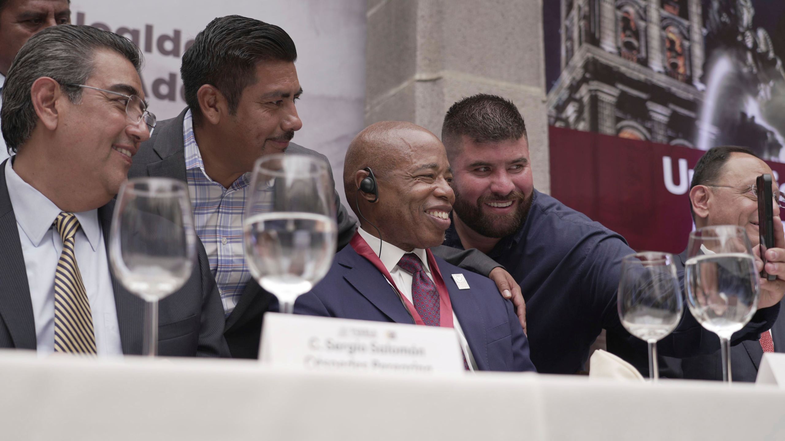 The Mayor of New York City Eric Adams, center, poses for selfies with local businessmen and dignitaries during an event at the former Municipal Palace in Puebla, Mexico, Thursday, Oct. 5, 2023. Adams is visiting the city, just outside the nation's capital, as part of a four-day trip to Latin America which he hopes will ease the burden of asylum seekers on New York. (AP Photo/Fernanda Pesce)